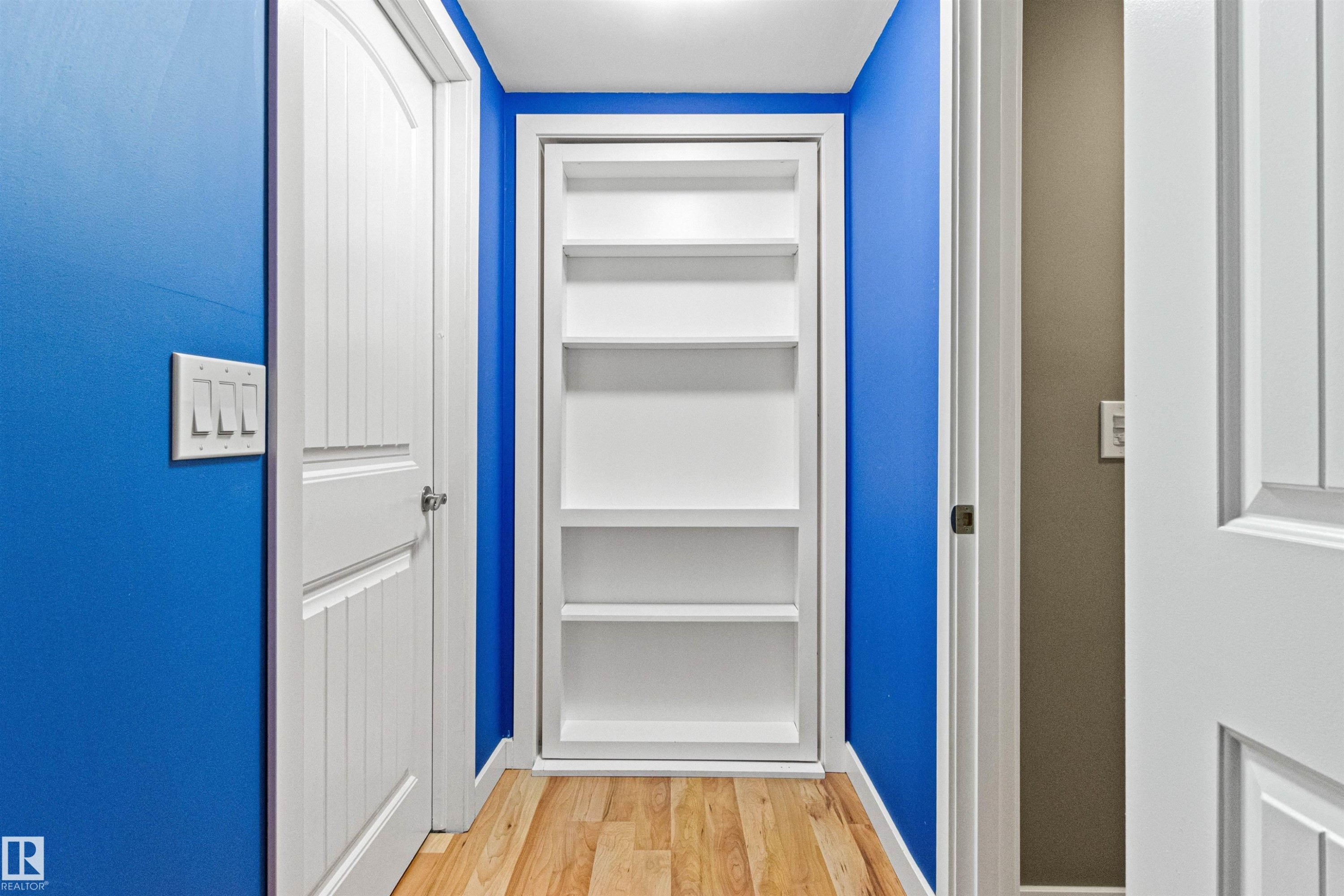Hallway featuring built-in shelving, paneled interior doors, light wood-finish flooring, and bright wall finishes - 1154 35A Avenue Nw, Edmonton, AB - Indoor Photo Showing Other Room