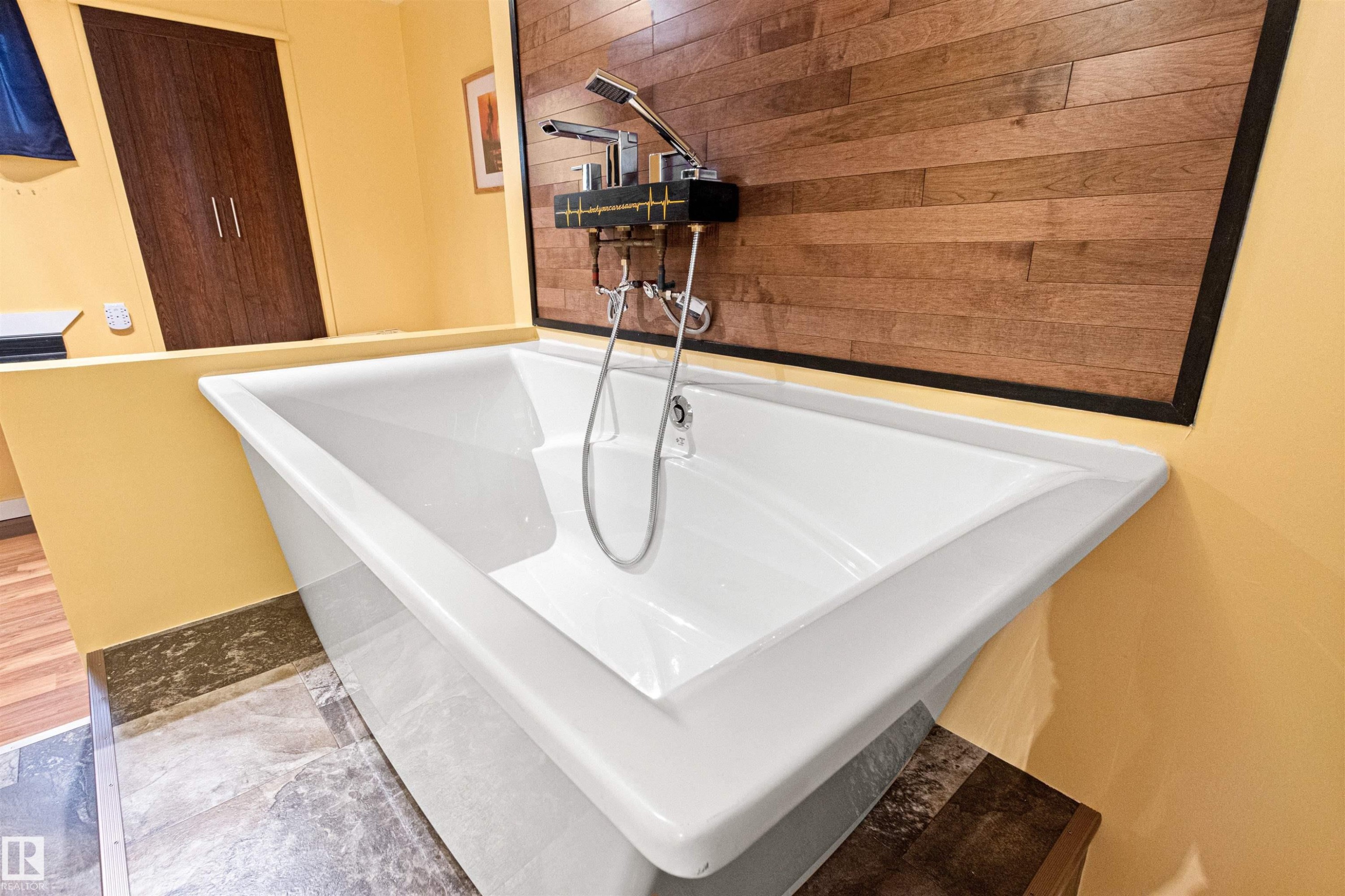 Freestanding soaking tub with polished chrome fixtures and a handheld shower - 1154 35A Avenue Nw, Edmonton, AB - Indoor