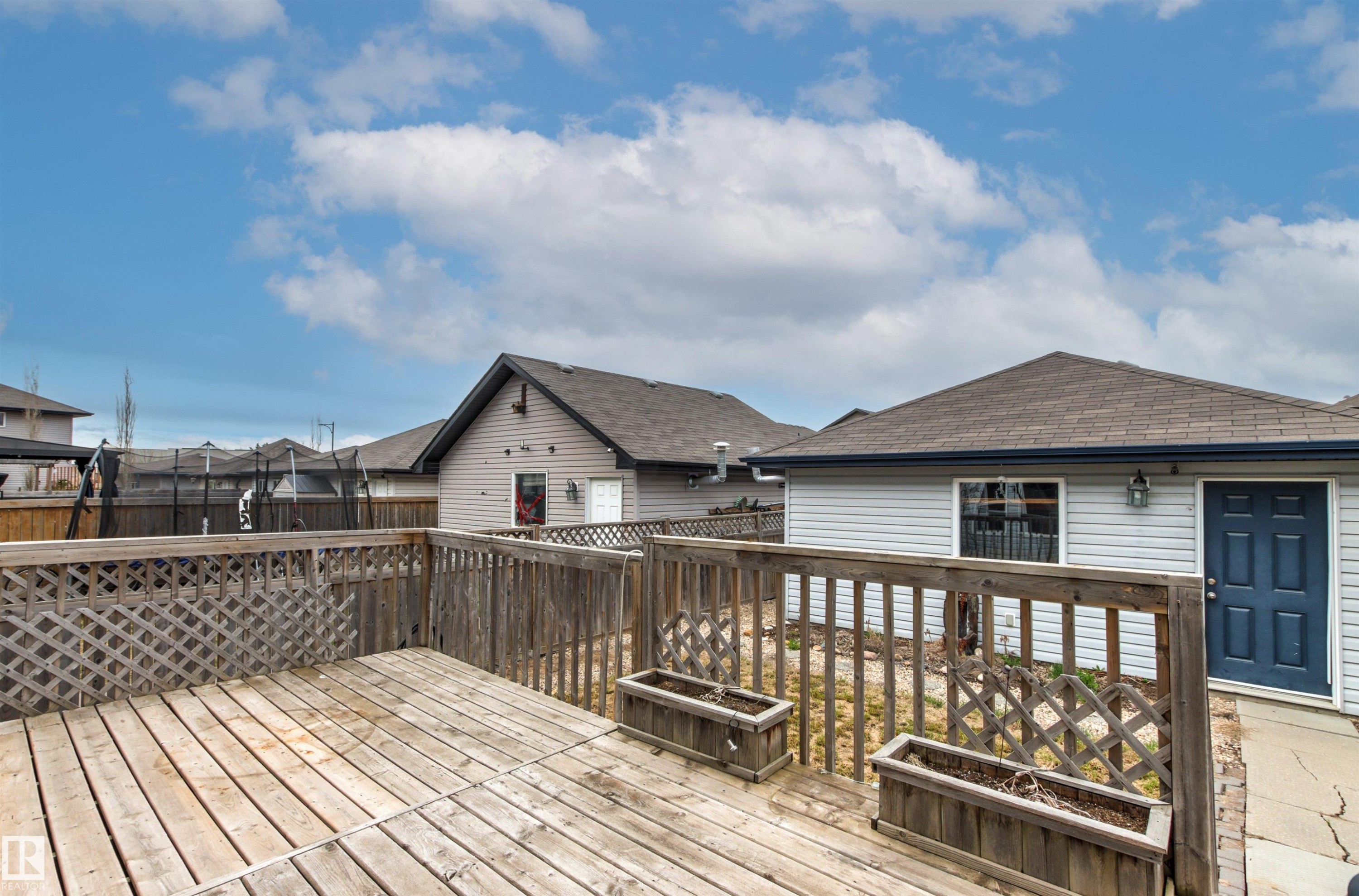 Expansive wooden deck with lattice railing, two planter boxes, and a direct entrance to the property - 1154 35A Avenue Nw, Edmonton, AB - Outdoor With Deck Patio Veranda With Exterior