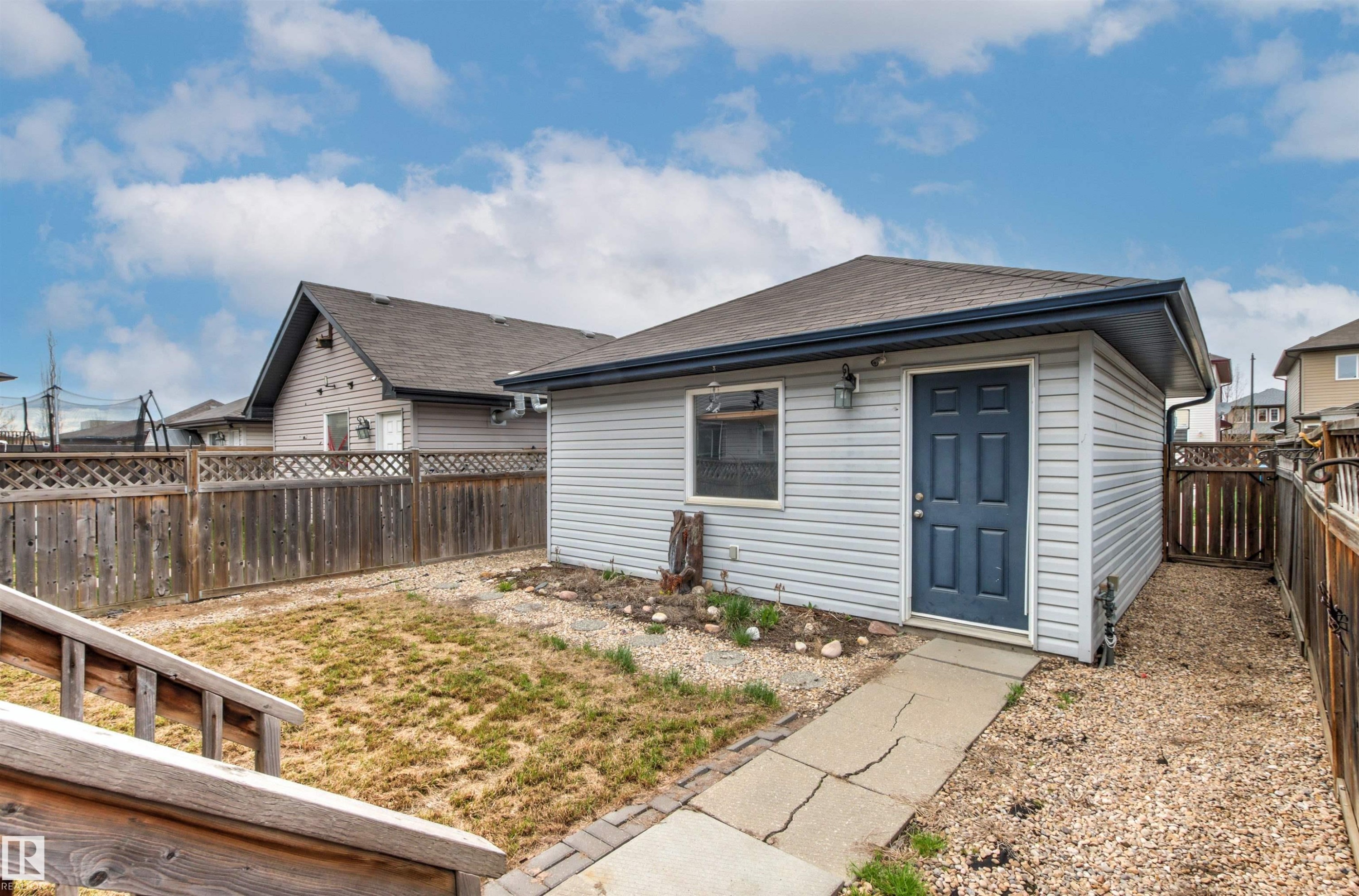 Detached accessory building featuring light gray siding, a dark blue entry door, and a single window - 1154 35A Avenue Nw, Edmonton, AB - Outdoor With Exterior