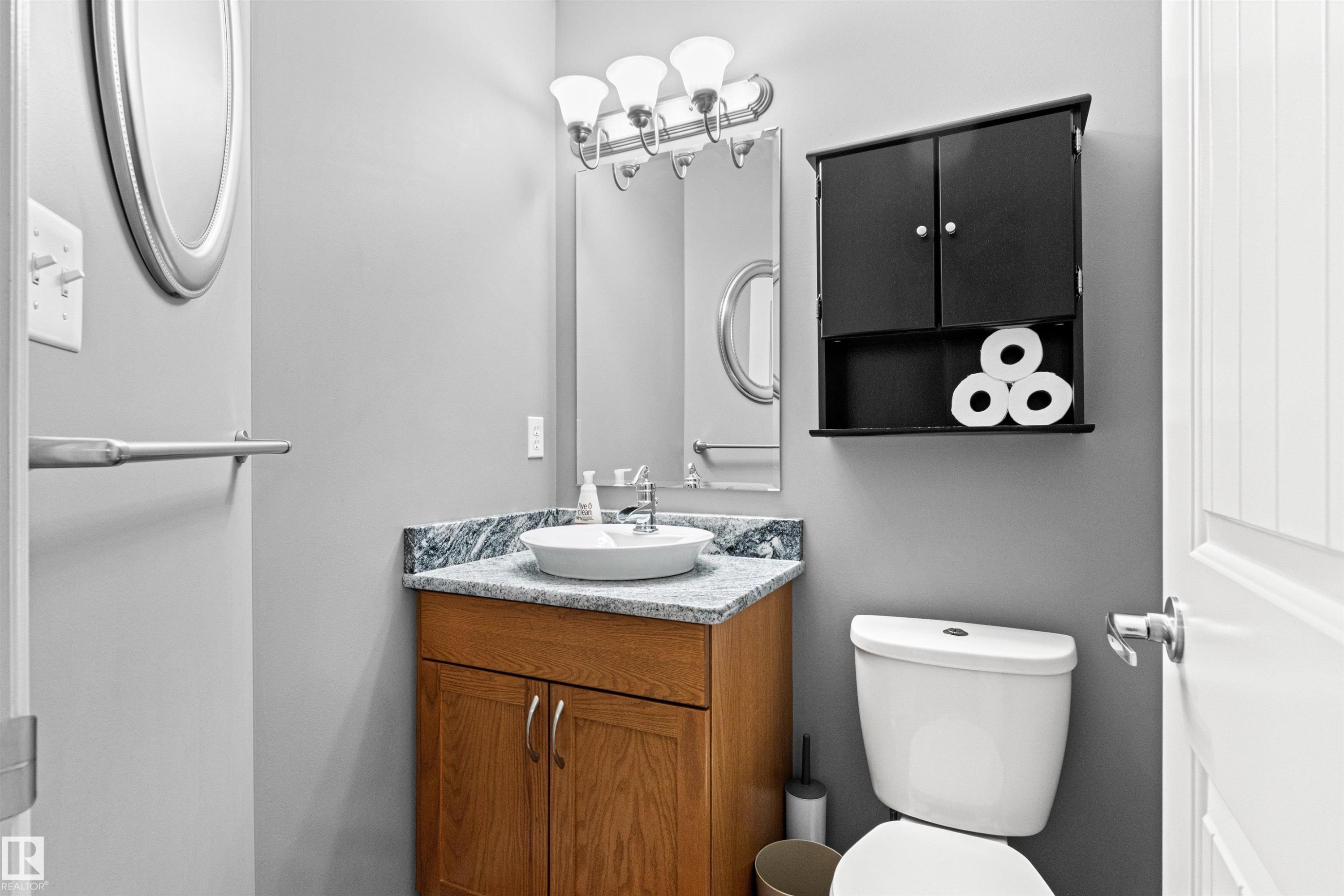 Bathroom featuring a vessel sink atop a wood-finish vanity with a stone countertop - 1154 35A Avenue Nw, Edmonton, AB - Indoor Photo Showing Bathroom
