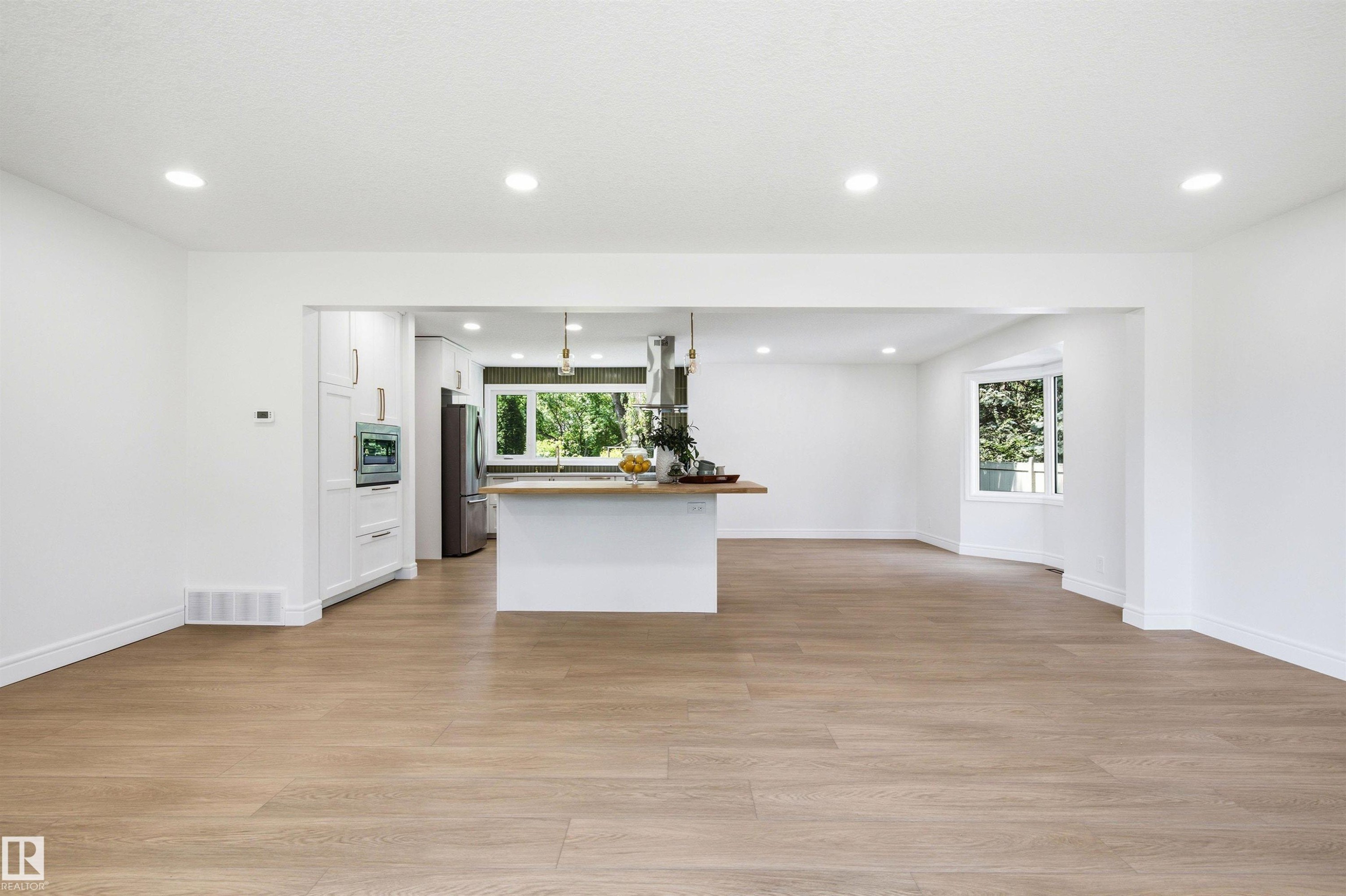 Spacious room featuring wood-finish flooring, recessed lighting, and a bay window - 14335 47 Avenue Nw, Edmonton, AB - Indoor