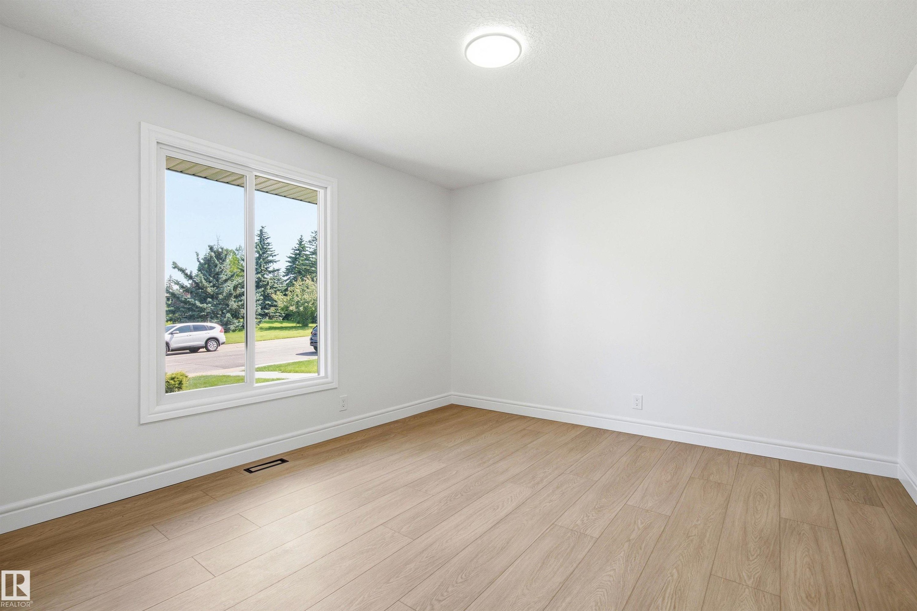 Bright room featuring wood-finish flooring, white baseboards, and a large window - 14335 47 Avenue Nw, Edmonton, AB - Indoor Photo Showing Other Room