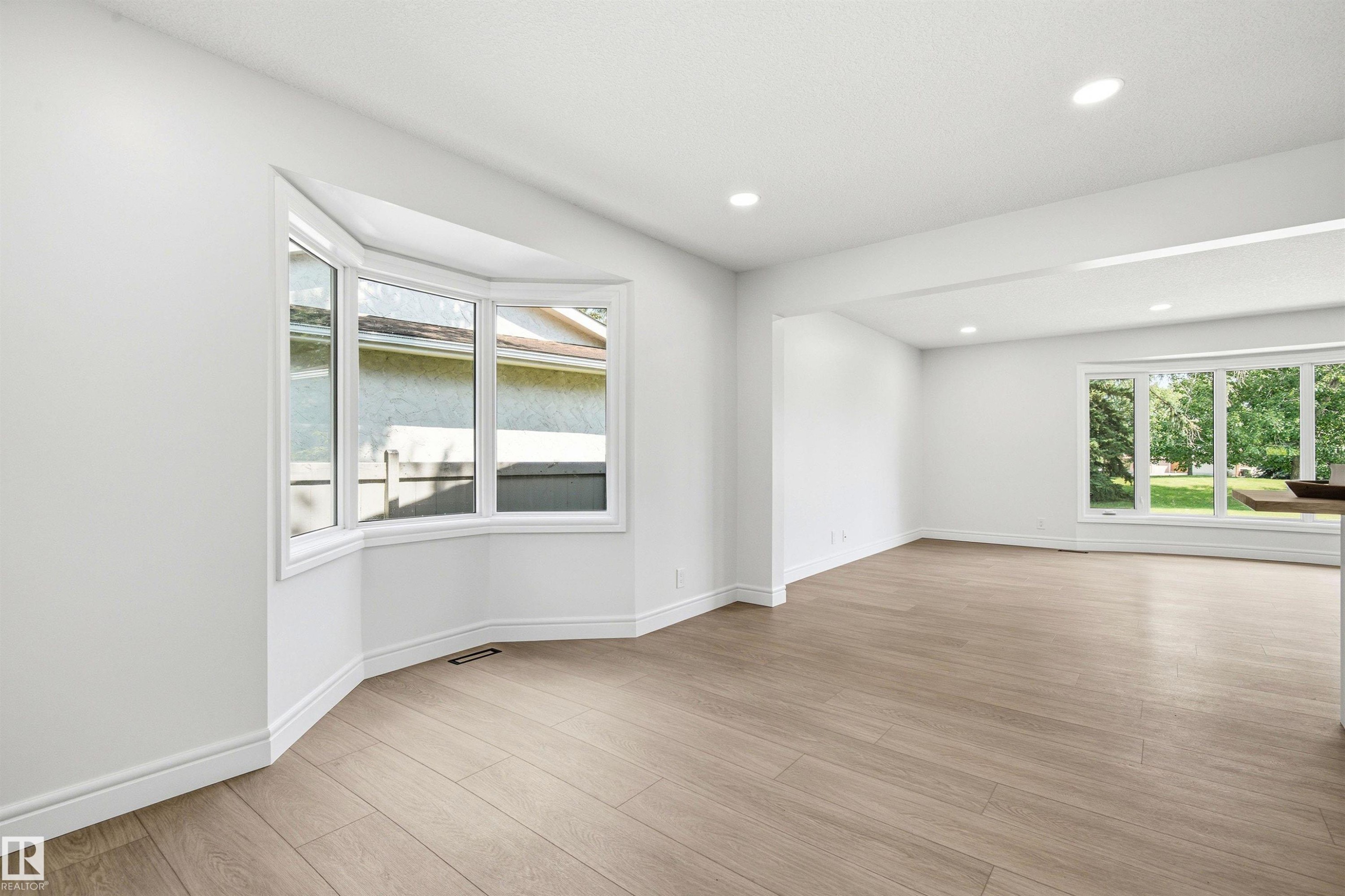 Open concept living space featuring a bay window, wood-finish flooring, recessed lighting, white walls, and a large picture window - 14335 47 Avenue Nw, Edmonton, AB - Indoor Photo Showing Other Room
