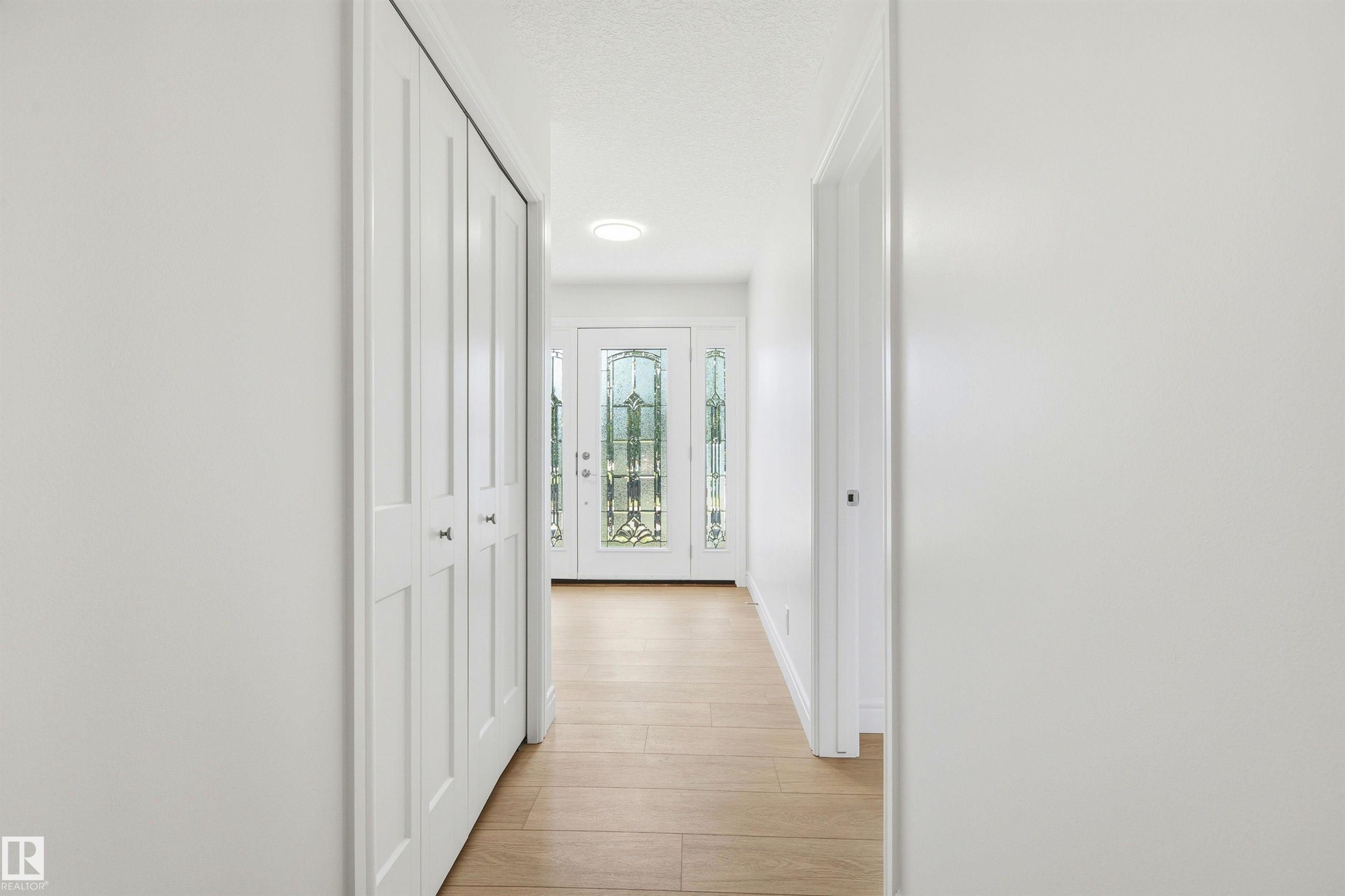 Entryway featuring wood-finish flooring, white bifold closet doors, recessed lighting, and a front door with decorative glass inserts - 14335 47 Avenue Nw, Edmonton, AB - Indoor Photo Showing Other Room