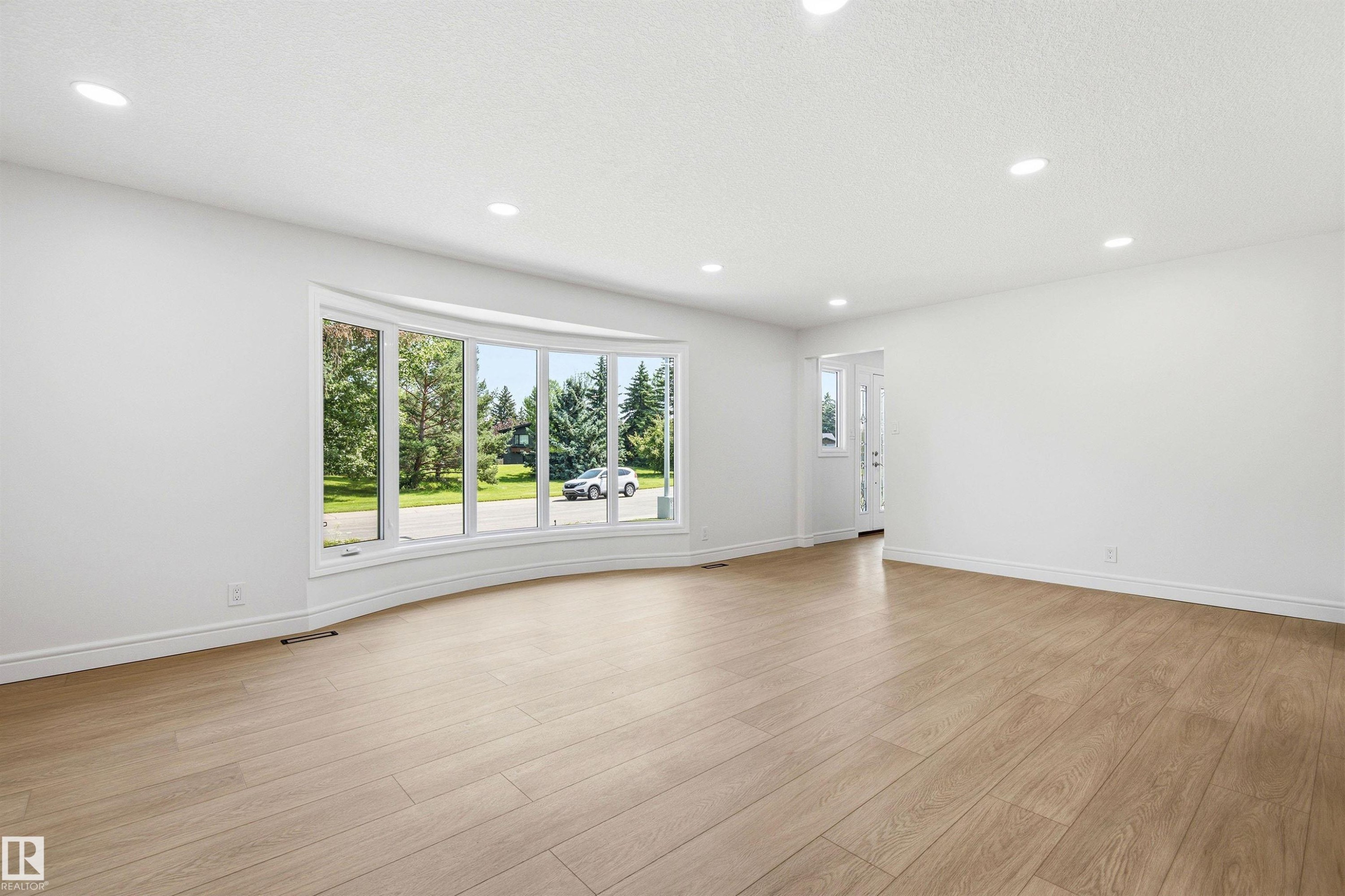 Spacious room featuring a curved bay window, wood-finish flooring, recessed lighting, and a white interior paint scheme - 14335 47 Avenue Nw, Edmonton, AB - Indoor