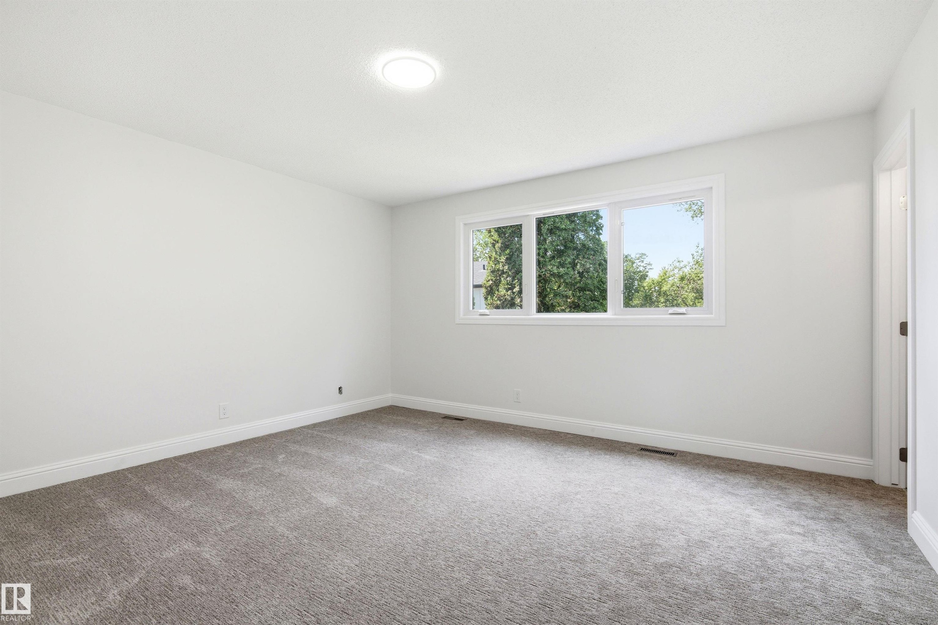 Spacious room featuring light gray carpeting, crisp white walls, and a recessed ceiling light - 14335 47 Avenue Nw, Edmonton, AB - Indoor Photo Showing Other Room