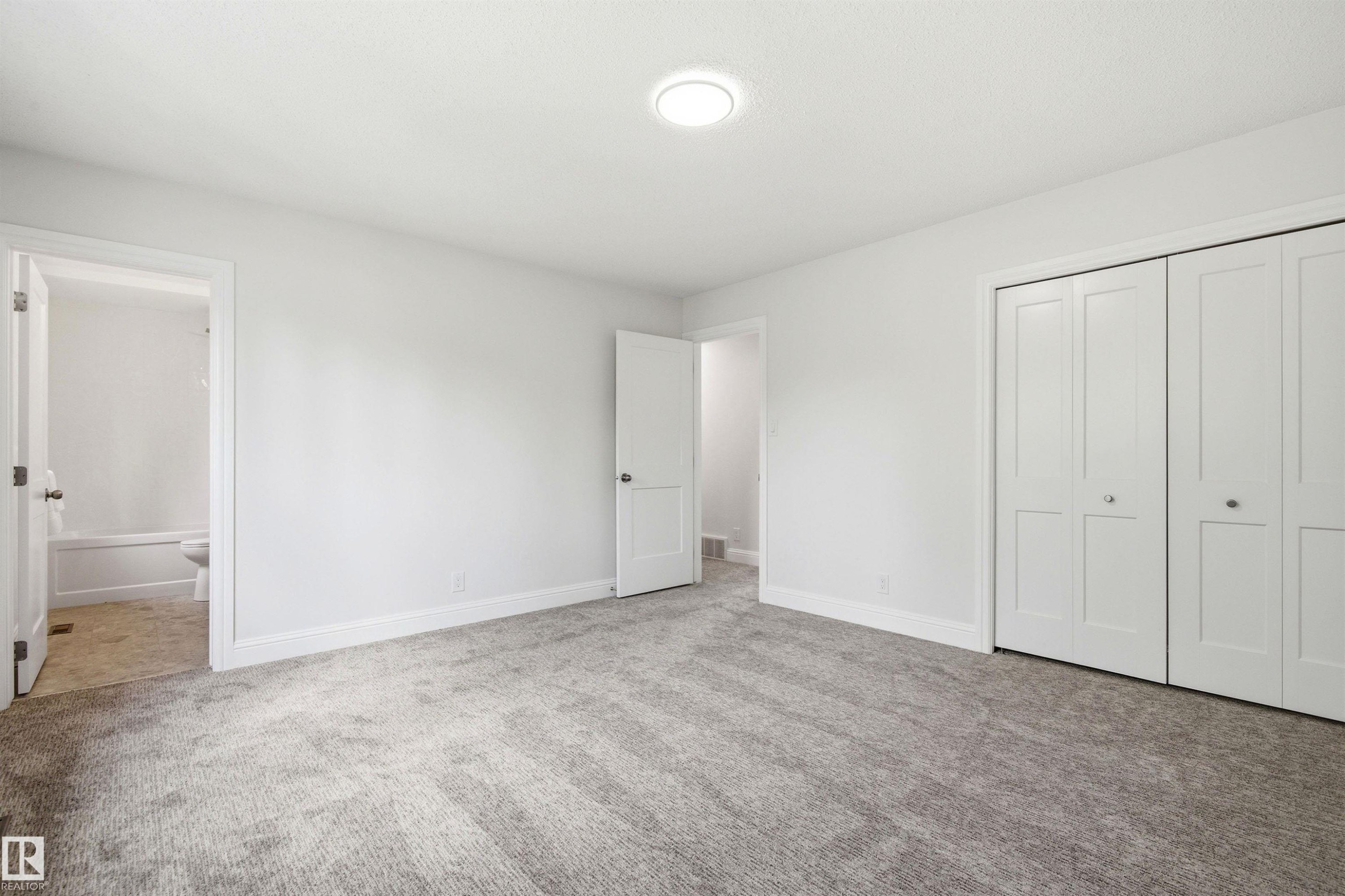 Spacious room featuring light gray carpeting, neutral wall paint, white trim, and a flush-mount ceiling light - 14335 47 Avenue Nw, Edmonton, AB - Indoor