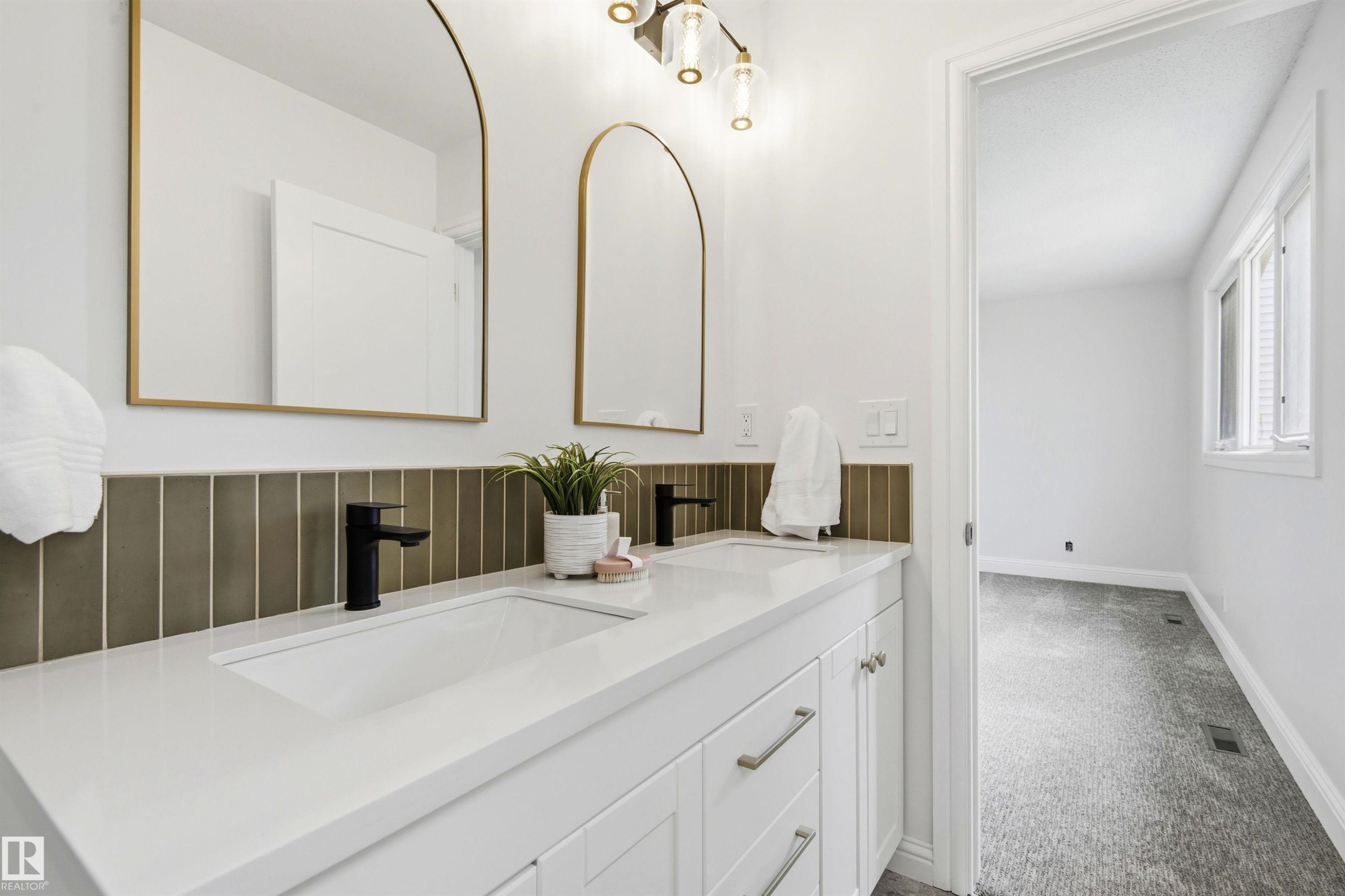 Double vanity with integrated sinks, white countertop, and matte black faucets - 14335 47 Avenue Nw, Edmonton, AB - Indoor Photo Showing Bathroom