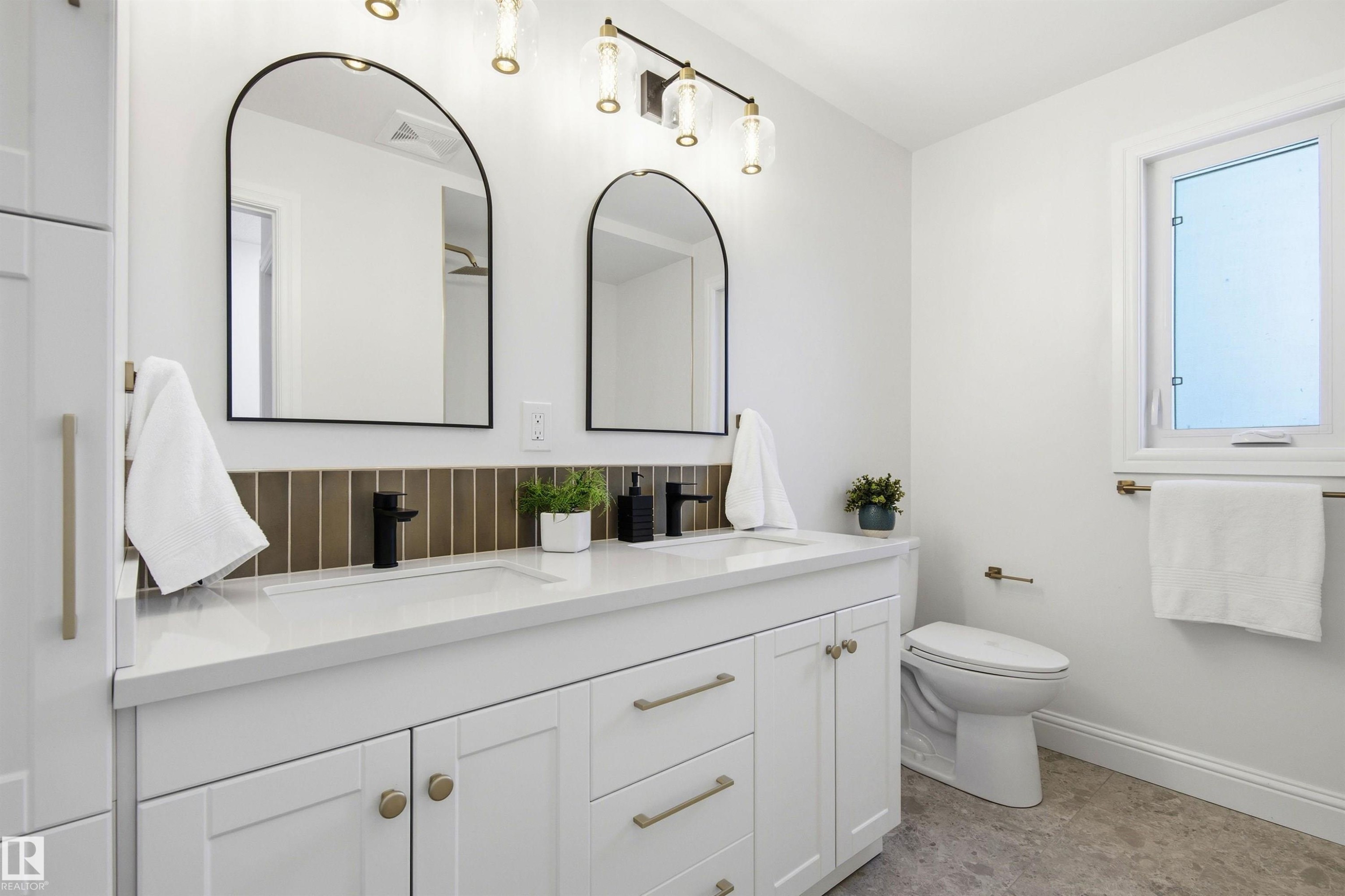 Double vanity featuring white shaker cabinetry with brass hardware, quartz countertop, and rectangular undermount sinks - 14335 47 Avenue Nw, Edmonton, AB - Indoor Photo Showing Bathroom