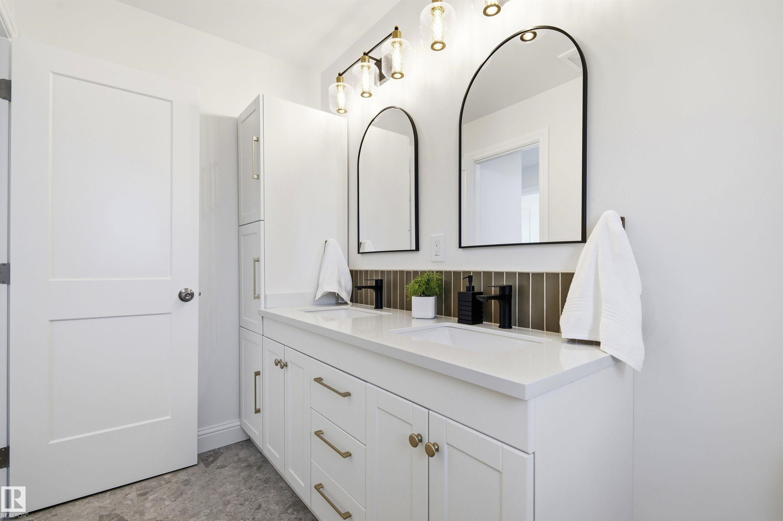 Double vanity featuring white cabinetry, brass hardware, and white countertops - 14335 47 Avenue Nw, Edmonton, AB - Indoor Photo Showing Other Room