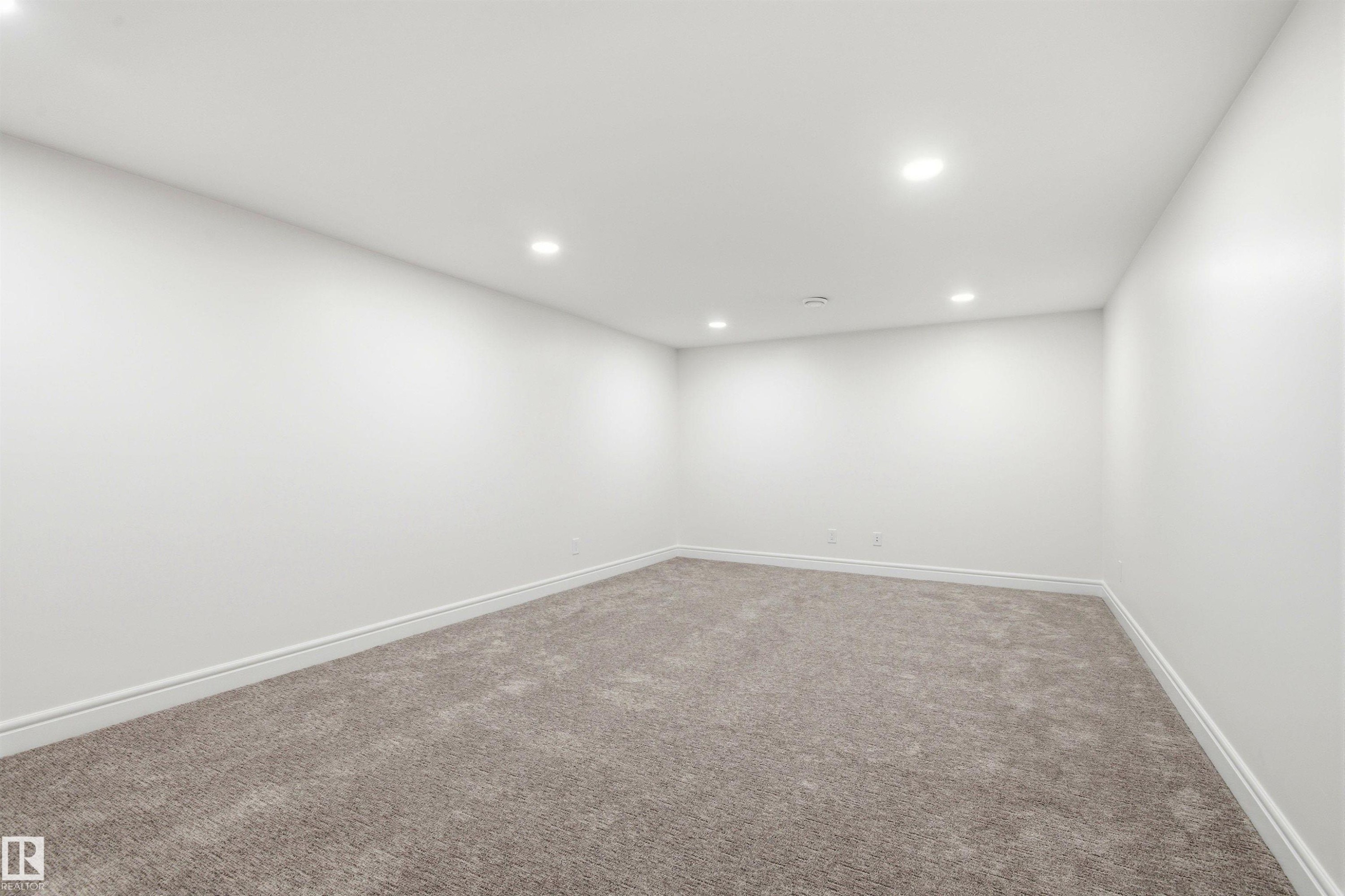 Spacious room featuring neutral carpeting, white walls, recessed ceiling lighting, and crisp white baseboards - 14335 47 Avenue Nw, Edmonton, AB - Indoor Photo Showing Other Room