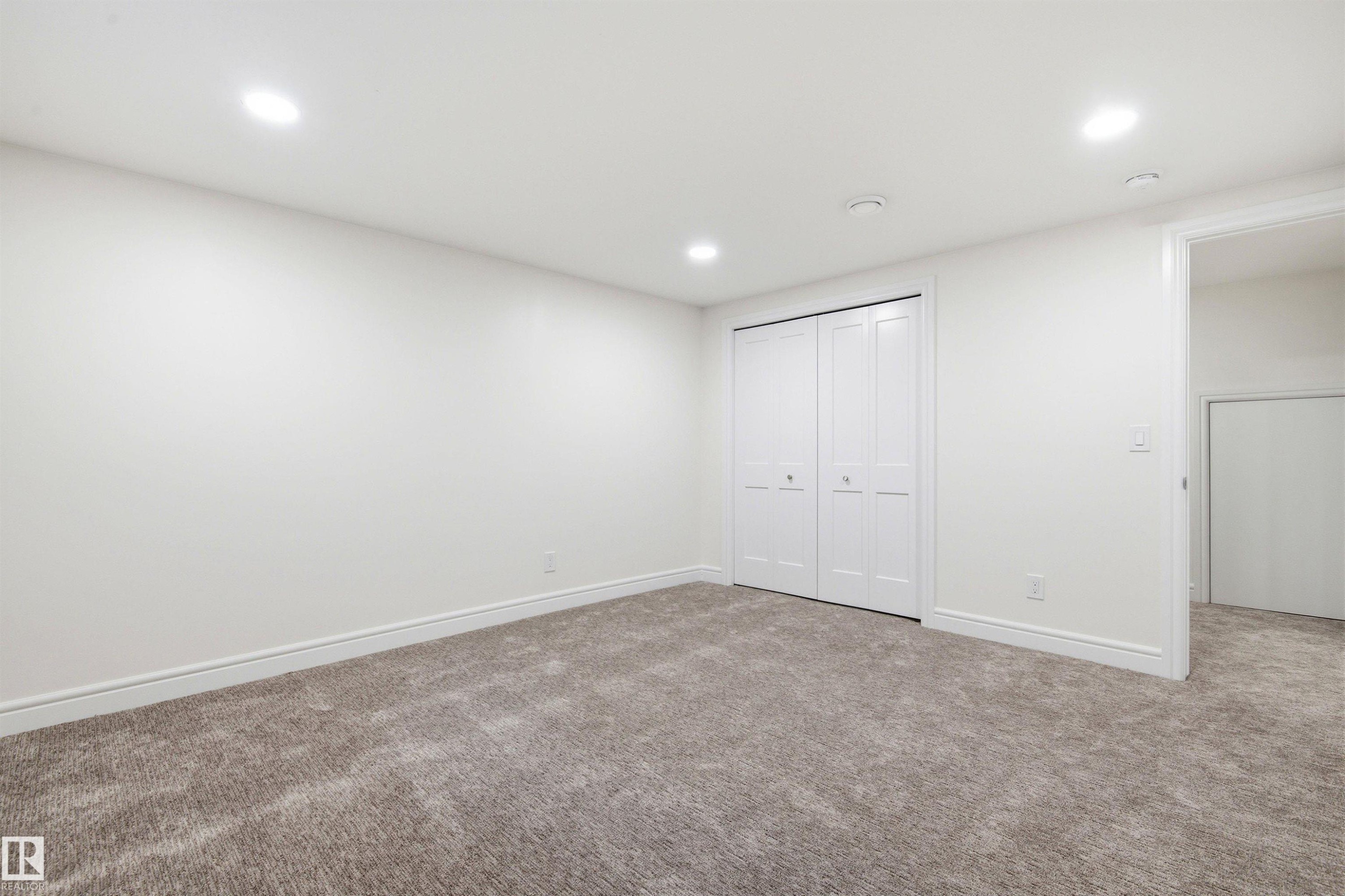 Carpeted room featuring white walls, recessed ceiling lighting, a bi-fold closet, and white baseboards - 14335 47 Avenue Nw, Edmonton, AB - Indoor Photo Showing Other Room