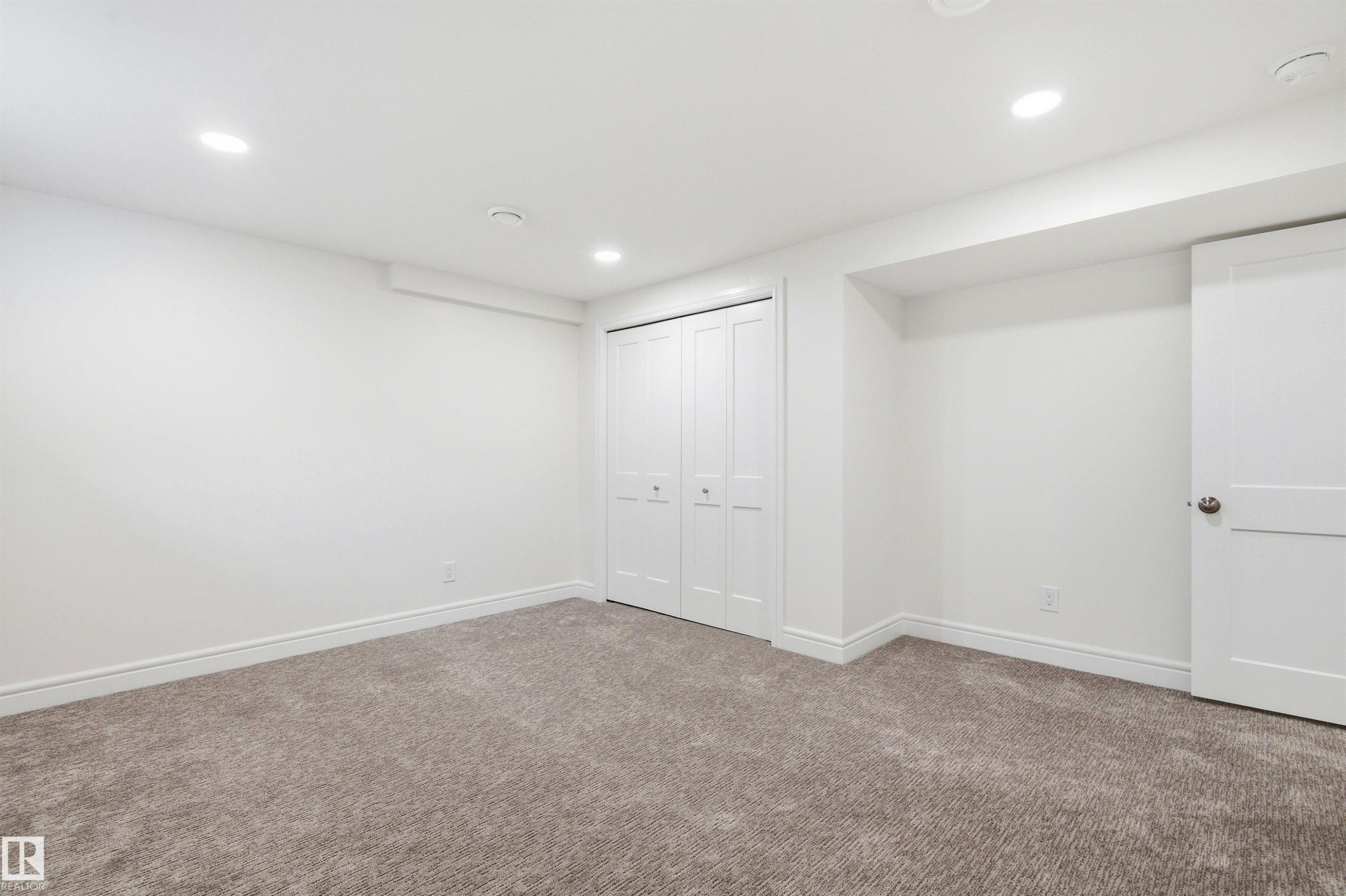 Neutral tone carpet flooring and white painted walls create a versatile interior - 14335 47 Avenue Nw, Edmonton, AB - Indoor Photo Showing Other Room