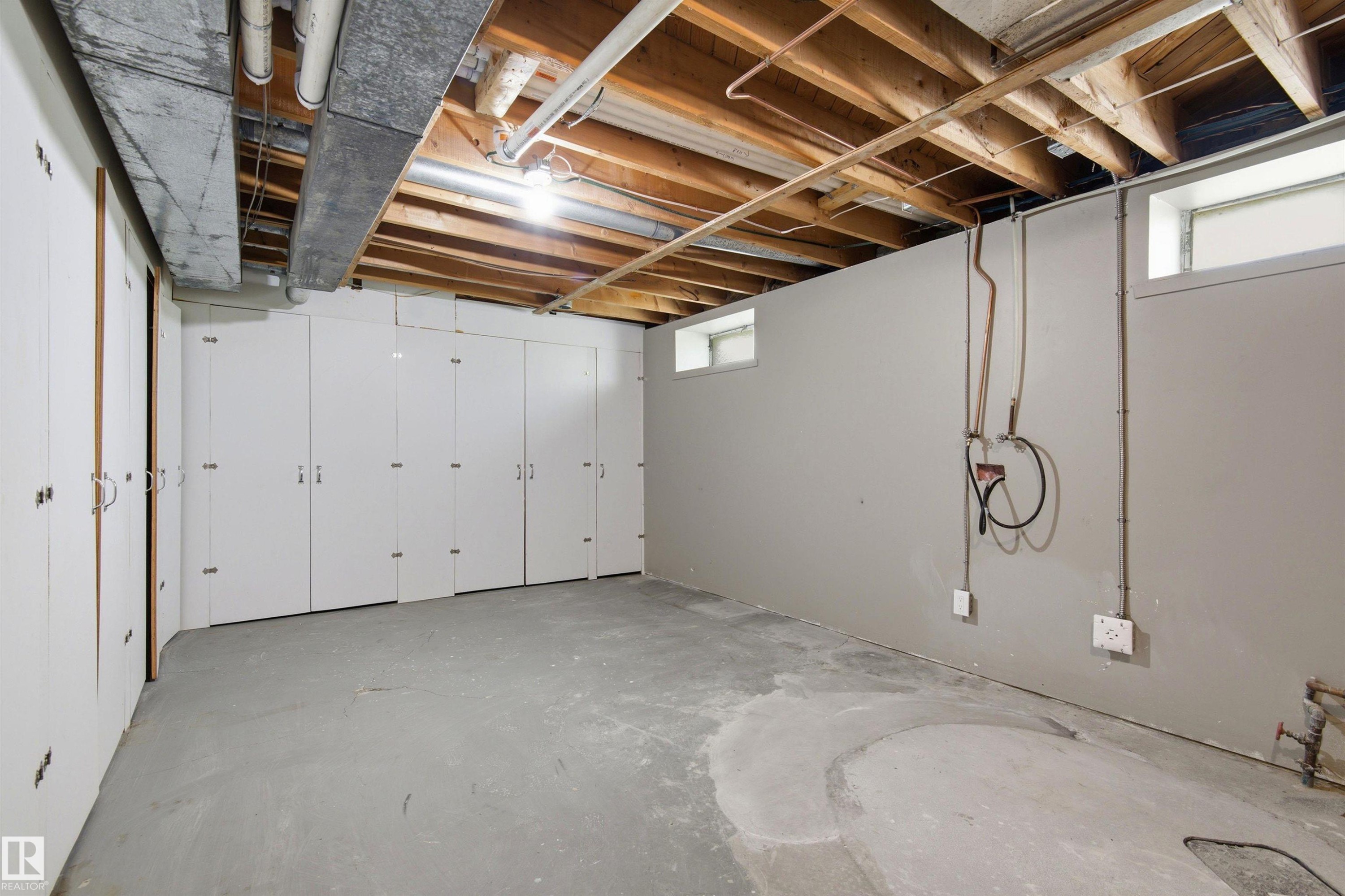 Expansive lower-level space featuring a concrete floor and exposed wood ceiling joists - 14335 47 Avenue Nw, Edmonton, AB - Indoor Photo Showing Basement