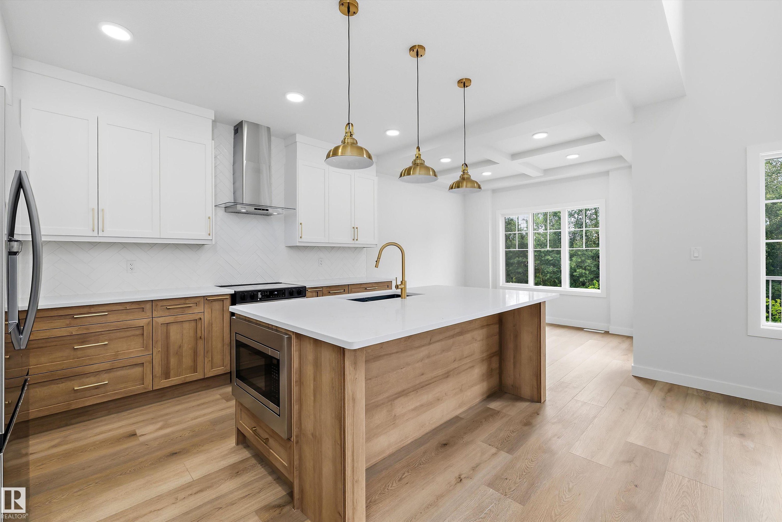 Spacious kitchen featuring an expansive center island, integrated microwave, stainless steel appliances, and a coffered ceiling - 919 Elderberry Landing Nw, Edmonton, AB - Indoor Photo Showing Kitchen With Upgraded Kitchen
