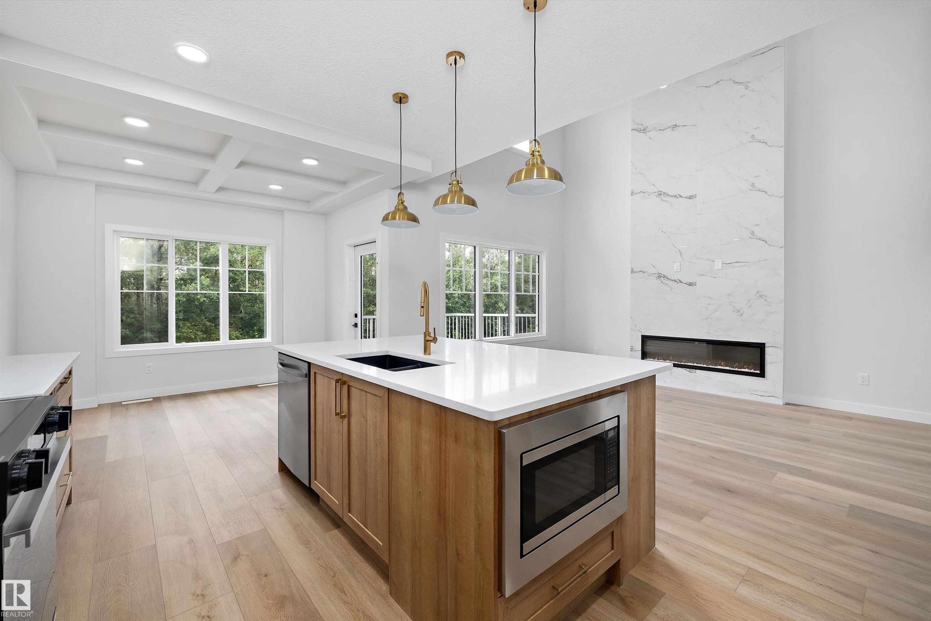 Open-concept living space featuring a central kitchen island with a built-in microwave, wood-finish flooring, and a coffered ceiling - 919 Elderberry Landing Nw, Edmonton, AB - Indoor Photo Showing Kitchen With Upgraded Kitchen