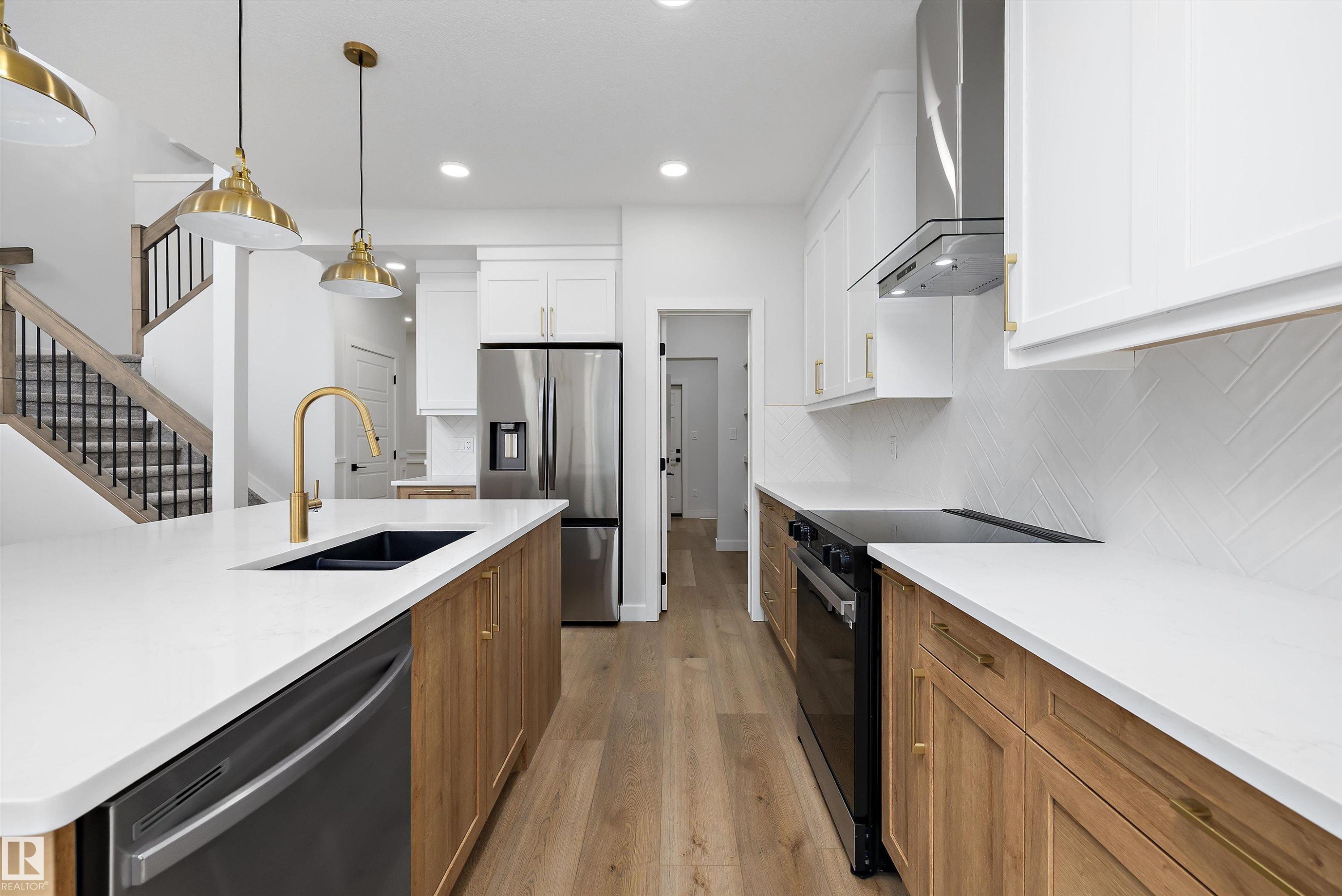 Modern kitchen featuring white cabinetry, light wood-finish lower cabinetry, and stainless steel appliances - 919 Elderberry Landing Nw, Edmonton, AB - Indoor Photo Showing Kitchen With Double Sink With Upgraded Kitchen