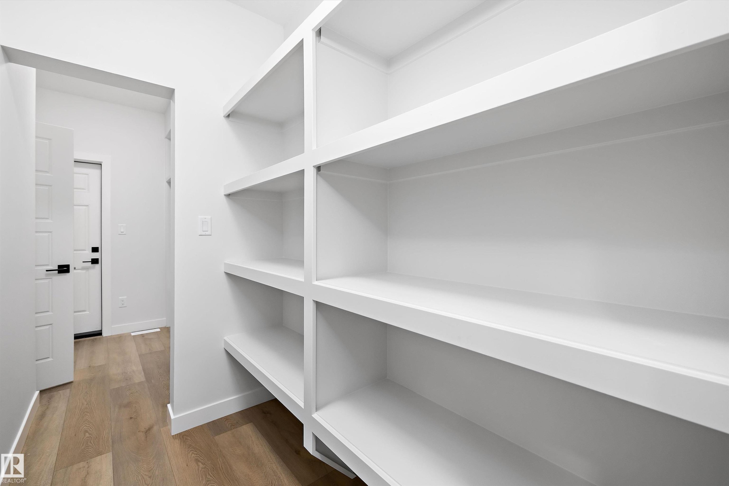 Built-in pantry shelving featuring white finishes and wood-finish flooring - 919 Elderberry Landing Nw, Edmonton, AB - Indoor With Storage