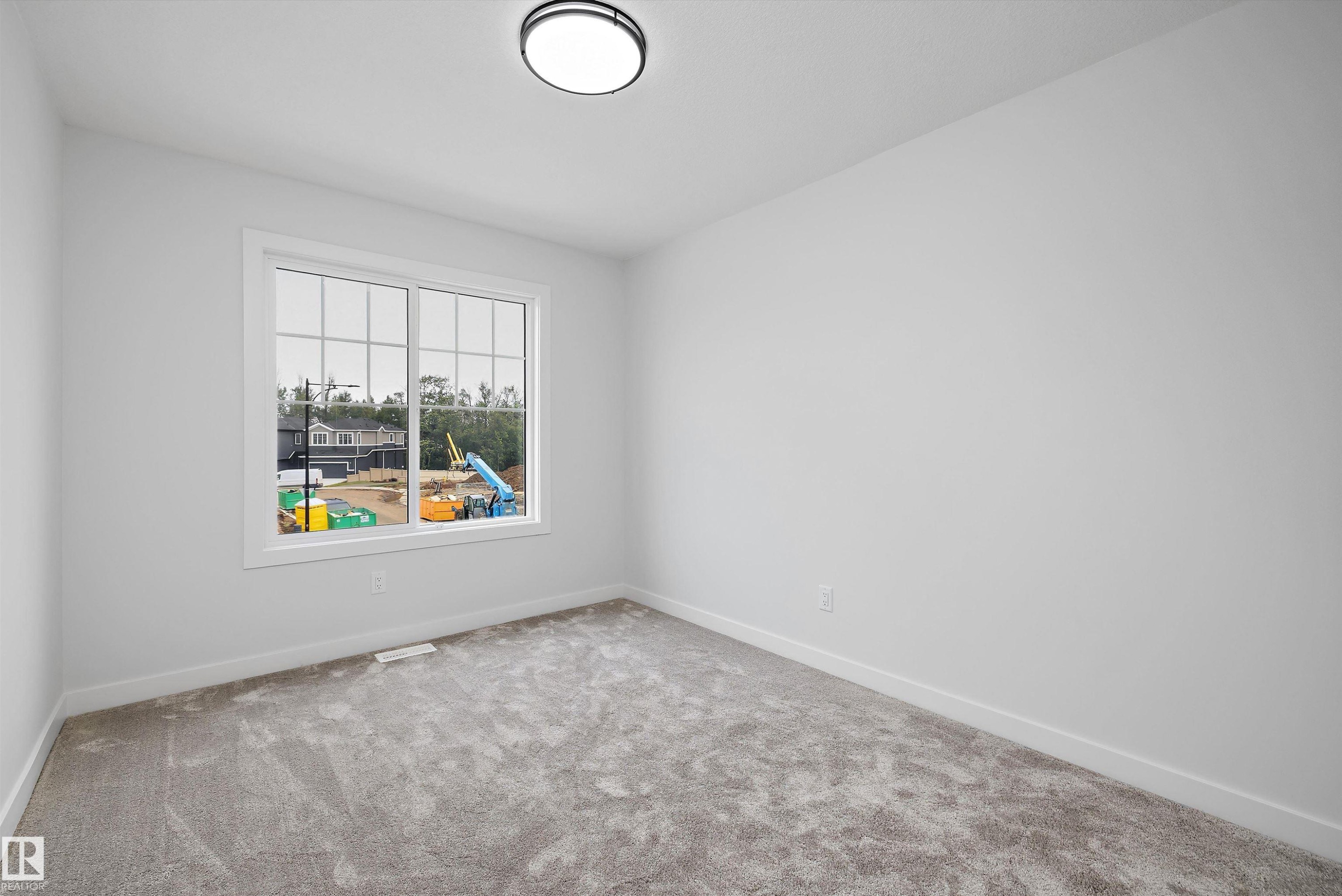 Bright room with a large window, neutral wall paint, gray carpet flooring, and a flush-mount ceiling light - 919 Elderberry Landing Nw, Edmonton, AB - Indoor Photo Showing Other Room