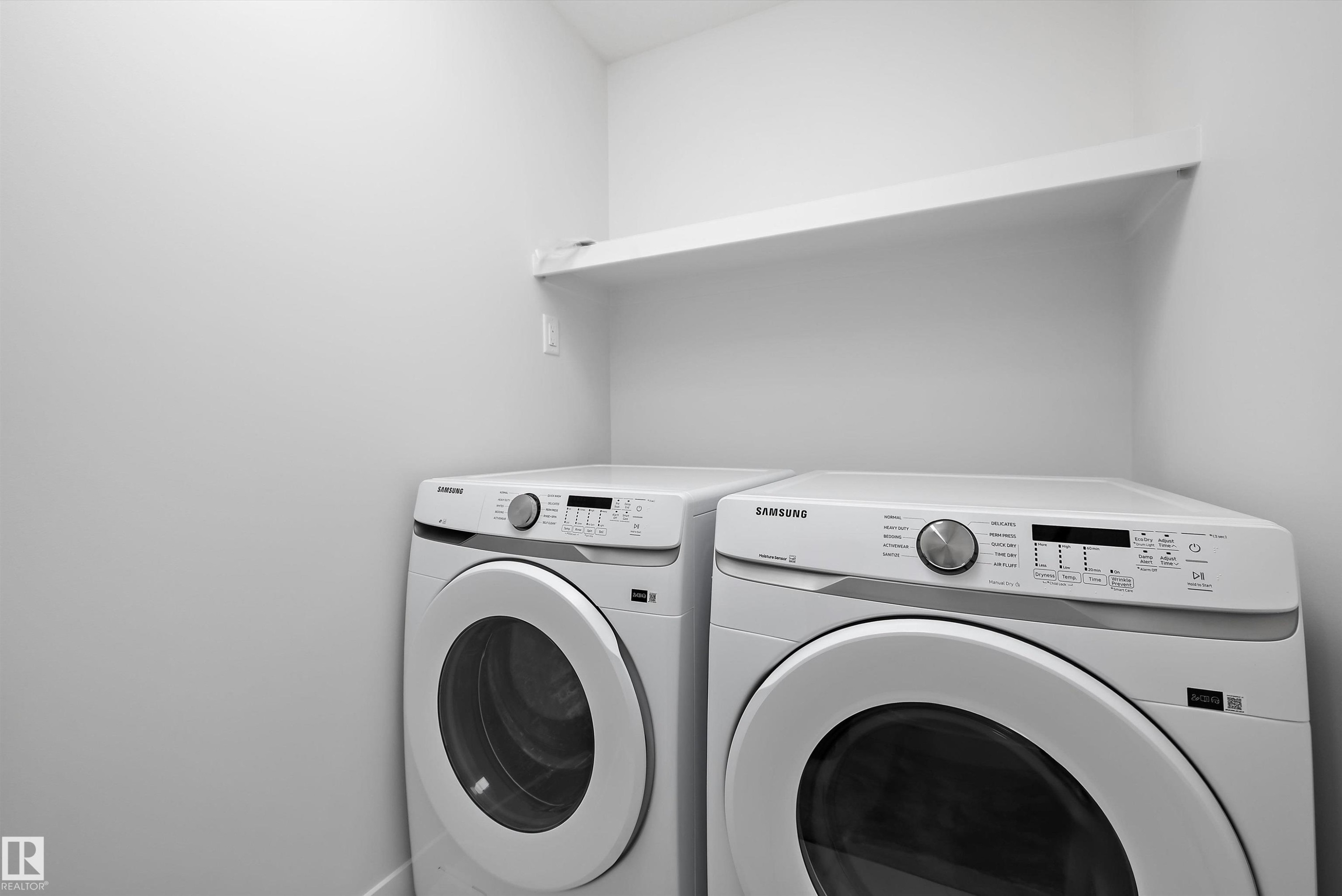 Dedicated laundry area featuring a white wall shelf, light neutral wall paint, and baseboard trim - 919 Elderberry Landing Nw, Edmonton, AB - Indoor Photo Showing Laundry Room
