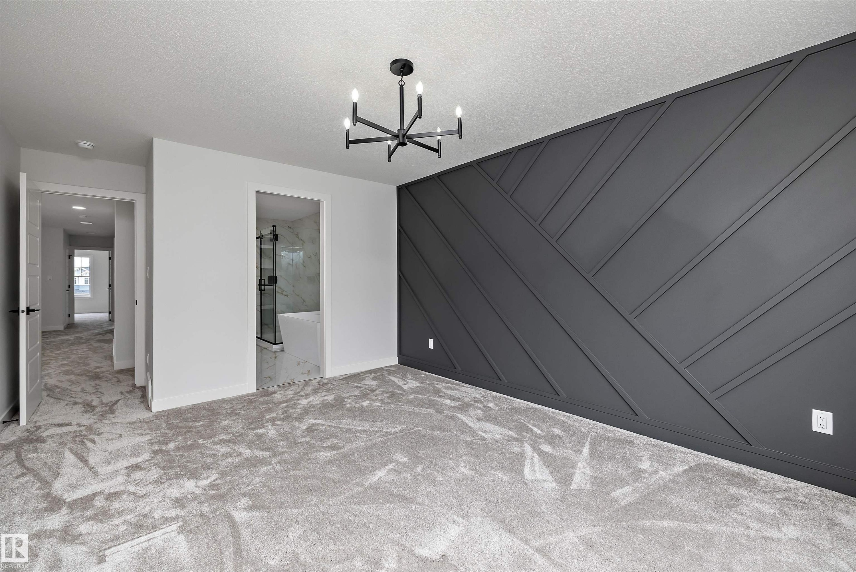 Spacious room featuring a decorative accent wall with geometric paneling, light gray carpeting, and a modern black chandelier - 919 Elderberry Landing Nw, Edmonton, AB - Indoor Photo Showing Other Room