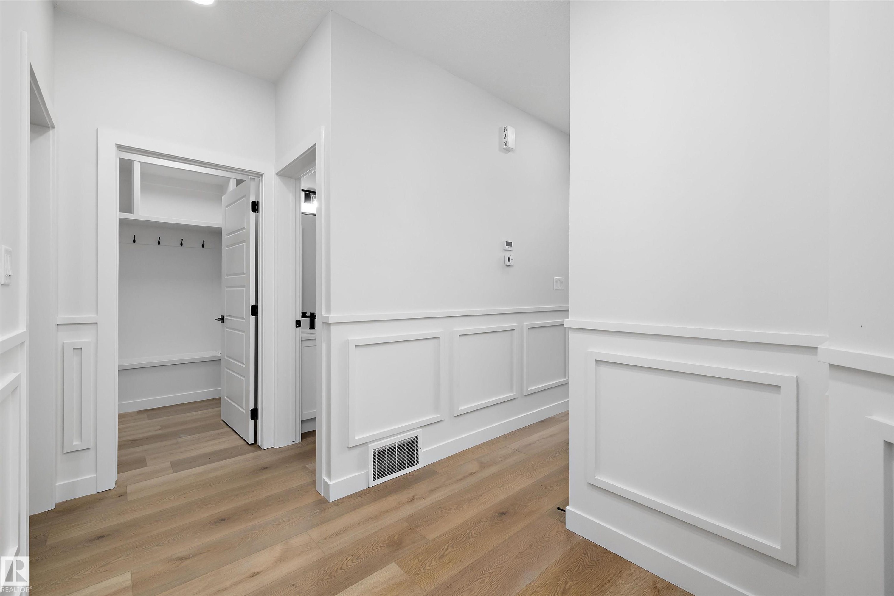 Entryway featuring wood-finish flooring, white paneled wainscoting, recessed ceiling lights, and a built-in storage bench with hooks - 919 Elderberry Landing Nw, Edmonton, AB - Indoor Photo Showing Other Room