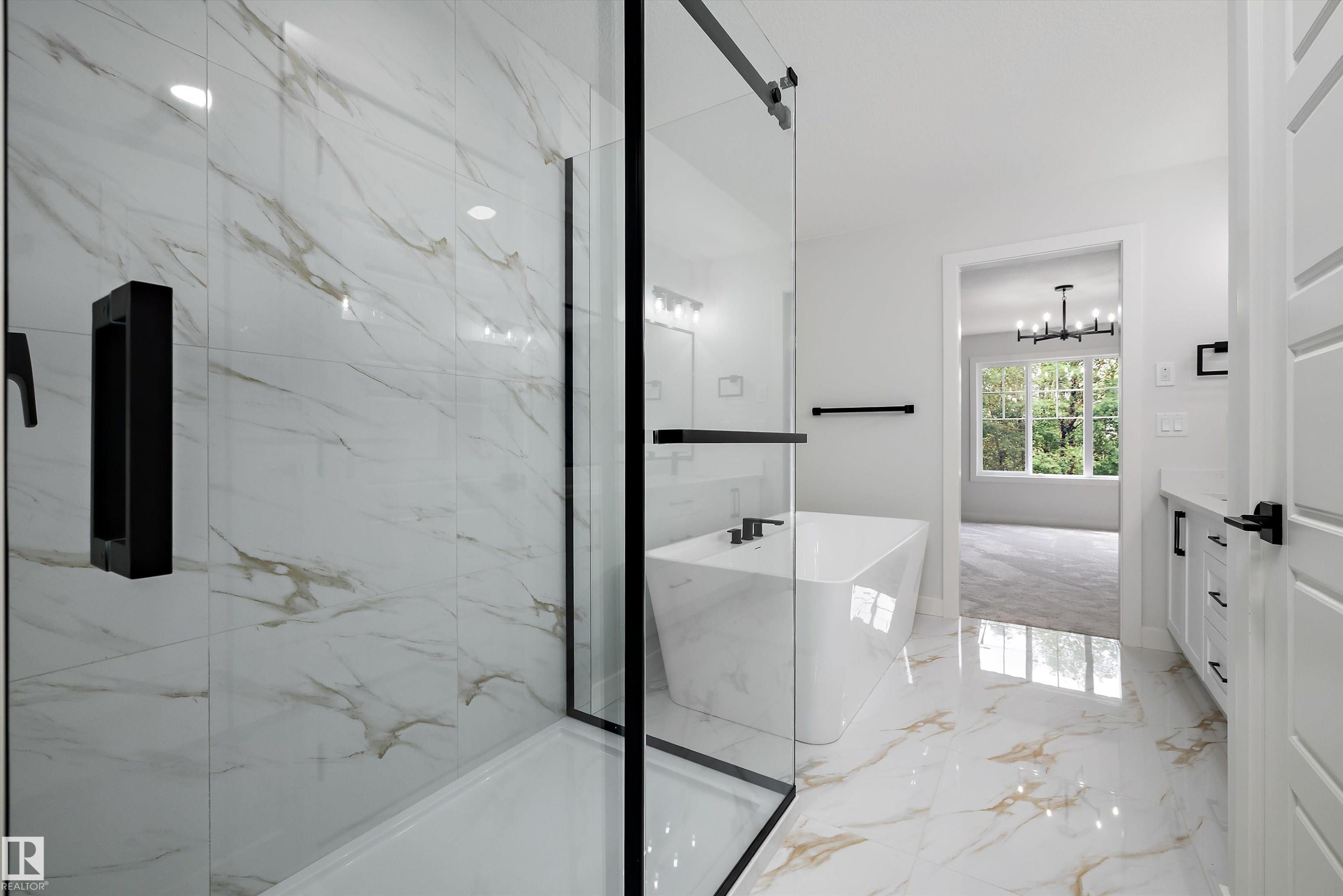Spacious bathroom featuring a frameless glass shower enclosure with black hardware, a freestanding soaking tub with black fixtures, and a white vanity with black hardware - 919 Elderberry Landing Nw, Edmonton, AB - Indoor Photo Showing Other Room