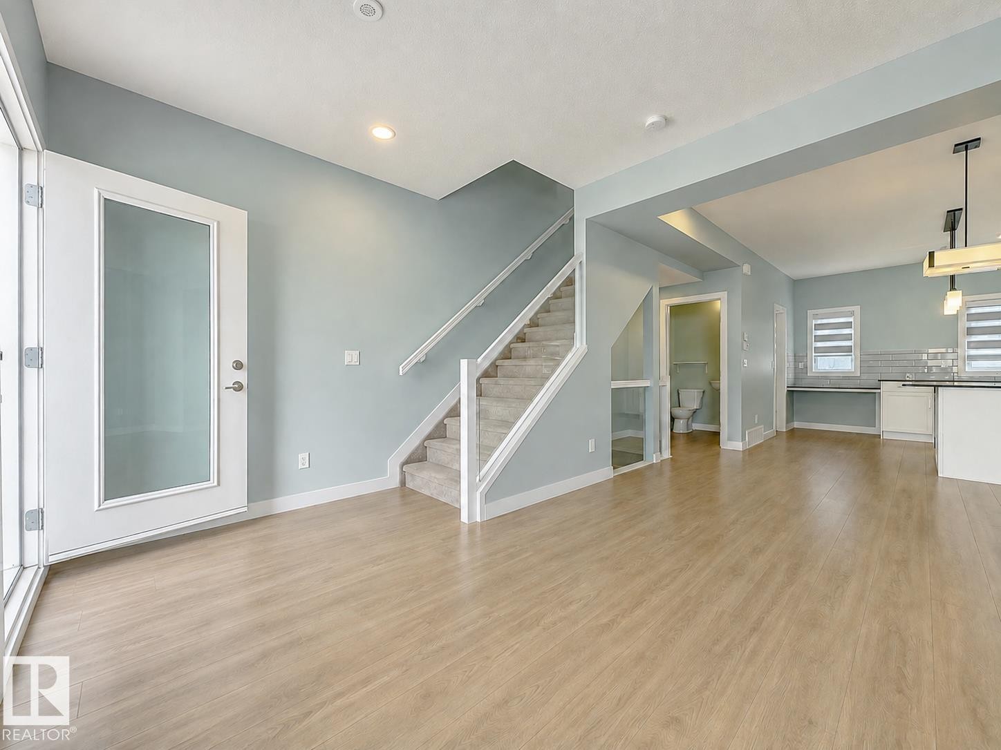 Wood-finish flooring throughout, carpeted staircase, recessed lighting, and a glass-paneled entry door - #56 804 Welsh Dr Sw, Edmonton, AB - Indoor