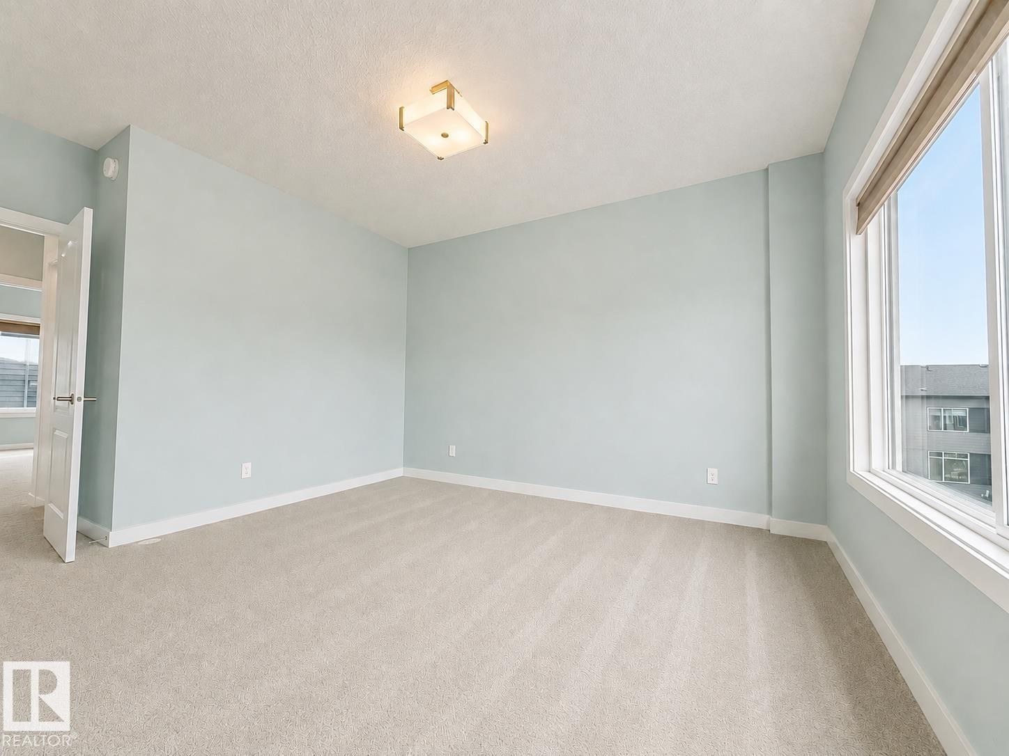Recessed ceiling lighting fixture, wall-to-wall carpeting, light-colored wall paint, white trim, and a large window - #56 804 Welsh Dr Sw, Edmonton, AB - Indoor Photo Showing Other Room