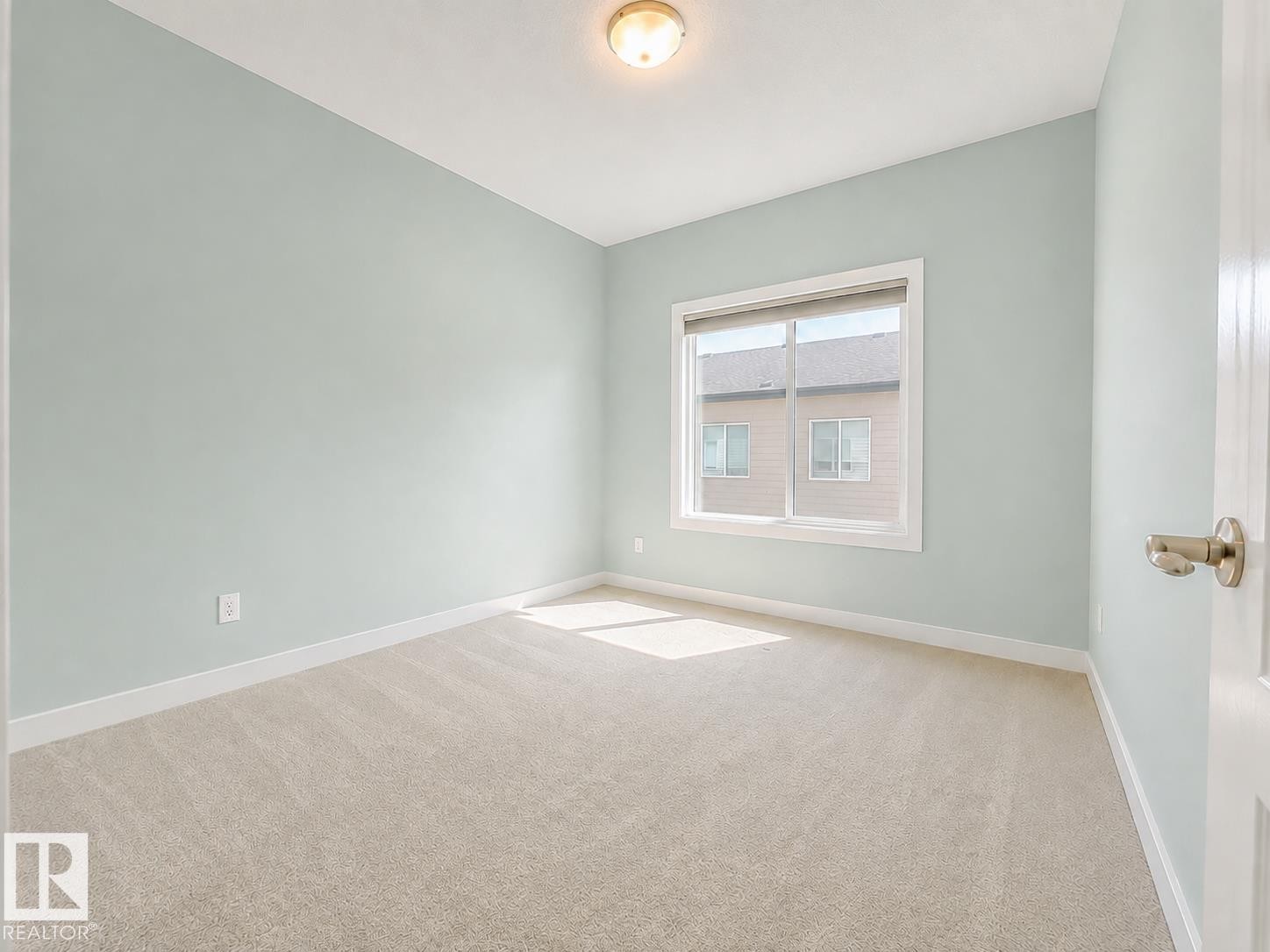 Neutral tone wall paint, window with white trim, beige carpet flooring, recessed ceiling light fixture, and white painted door - #56 804 Welsh Dr Sw, Edmonton, AB - Indoor Photo Showing Other Room