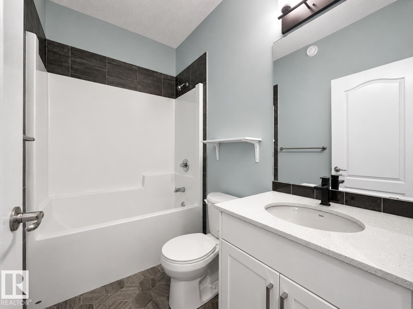White vanity with a light-colored countertop, undermount sink, and matte black faucet - #56 804 Welsh Dr Sw, Edmonton, AB - Indoor Photo Showing Bathroom