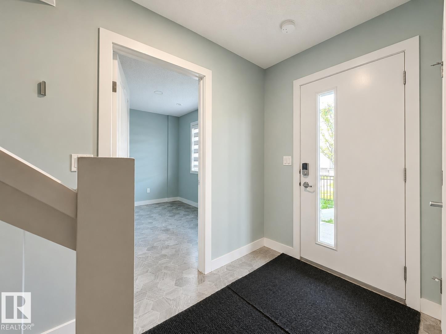 Entryway featuring a white door with a vertical glass insert, smart lock hardware, light blue-grey wall paint, and white trim - #56 804 Welsh Dr Sw, Edmonton, AB - Indoor Photo Showing Other Room