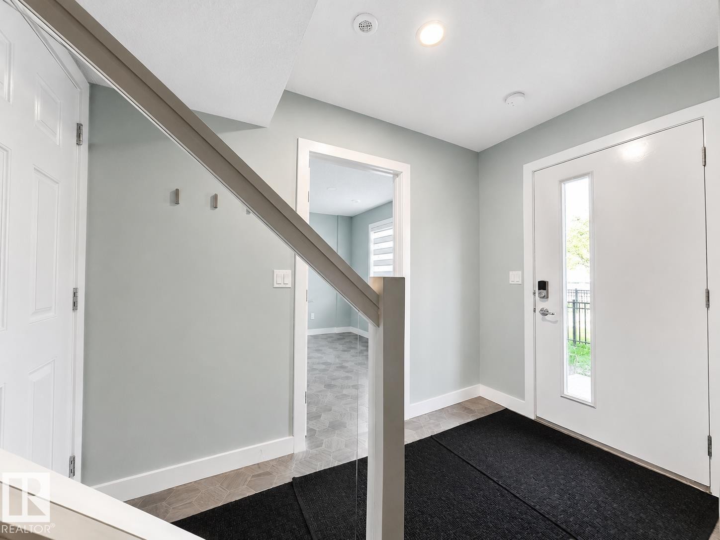 Entryway featuring a white front door with a vertical window, recessed lighting, and light grey walls - #56 804 Welsh Dr Sw, Edmonton, AB - Indoor Photo Showing Other Room
