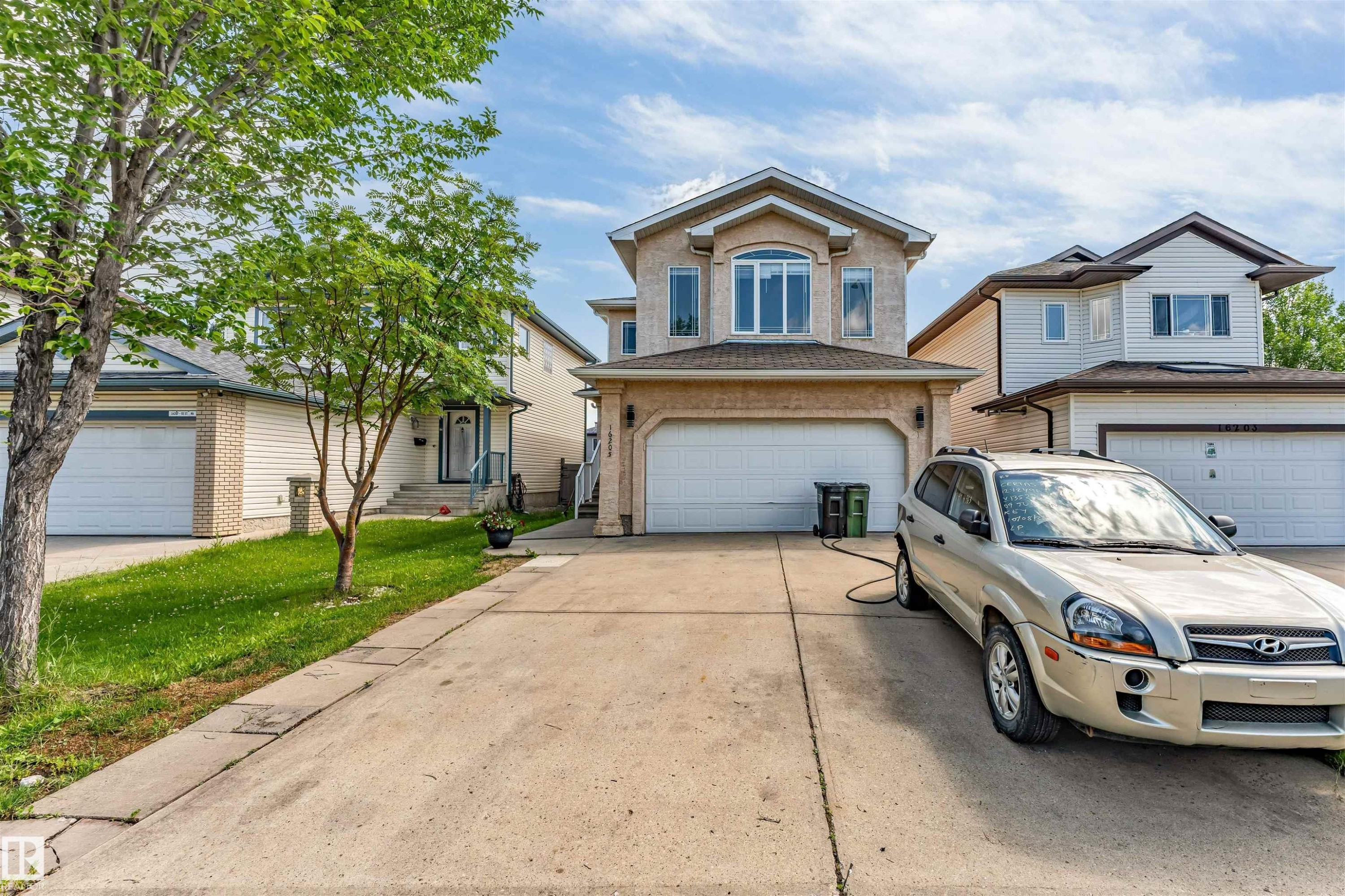Two-story residential property featuring a stucco exterior with a prominent arched window on the second level - 16205 55 Street Nw, Edmonton, AB - Outdoor With Facade