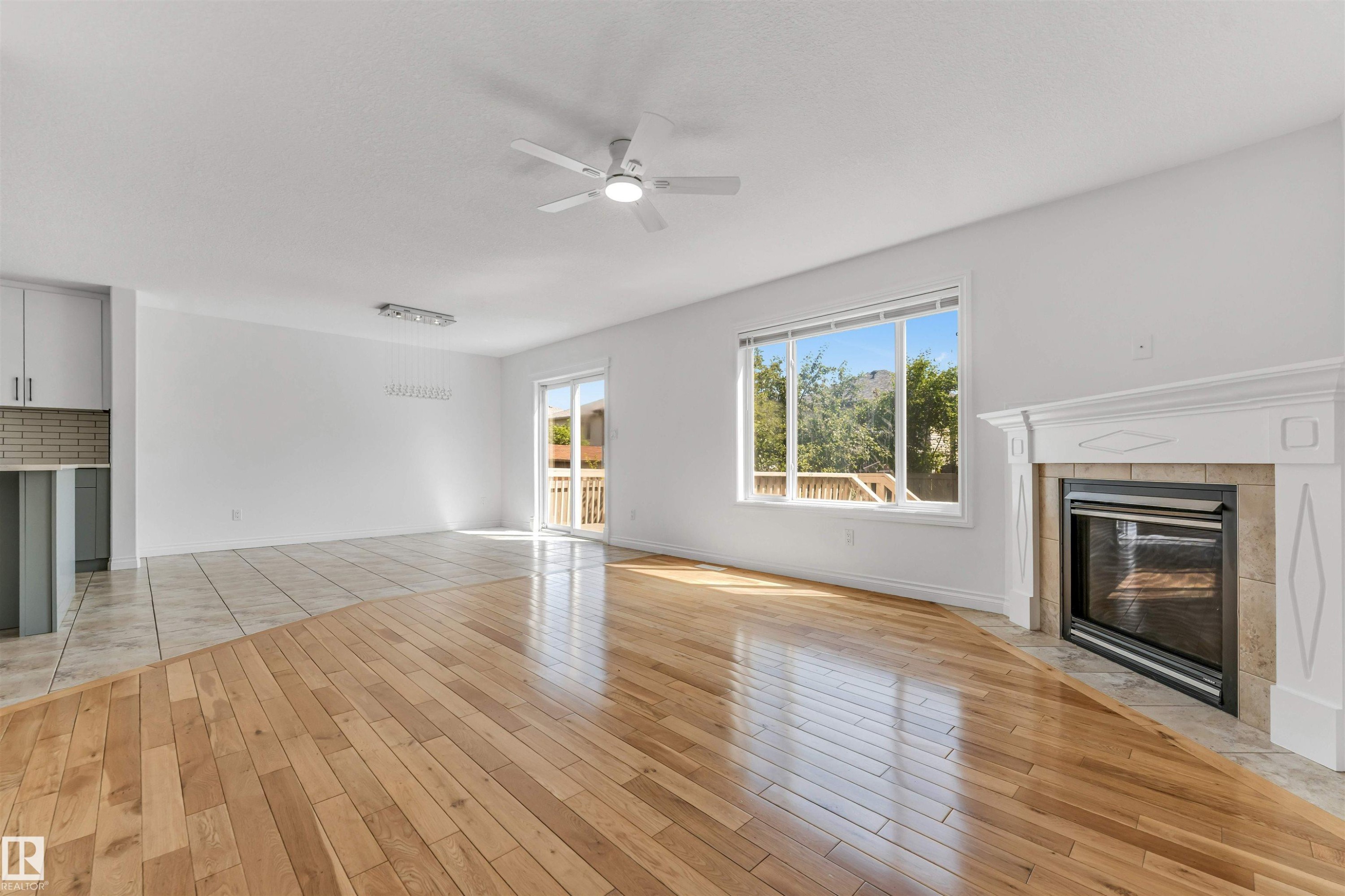 Living area featuring hardwood flooring, a gas fireplace with a decorative mantel, and a sliding glass door leading to an outdoor deck - 16205 55 Street Nw, Edmonton, AB - Indoor With Fireplace