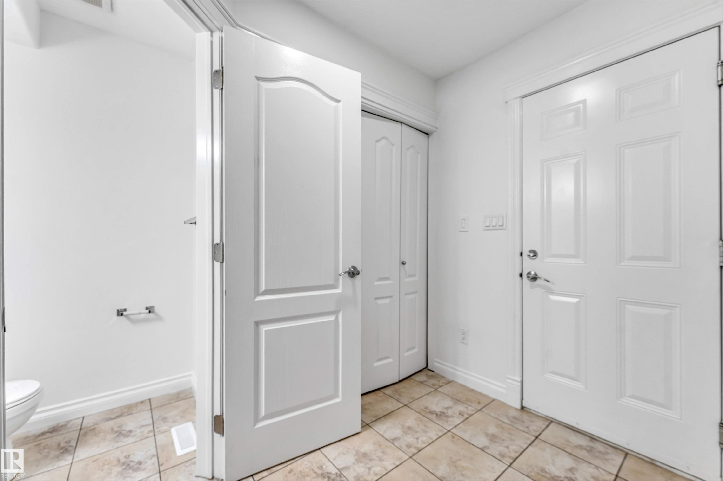 Entry area featuring light-toned tile flooring and white trim - 16205 55 Street Nw, Edmonton, AB - Indoor Photo Showing Other Room