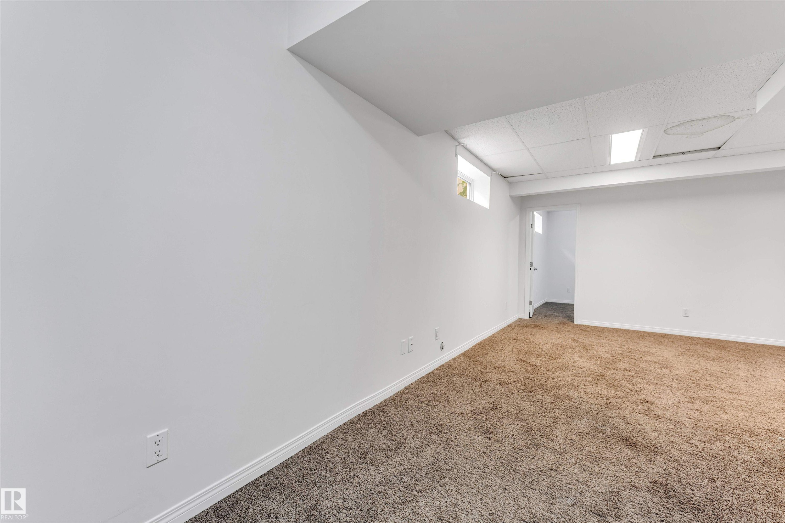 Spacious room with plush brown carpeting, white baseboards, and a white ceiling with recessed lighting - 16205 55 Street Nw, Edmonton, AB - Indoor Photo Showing Other Room