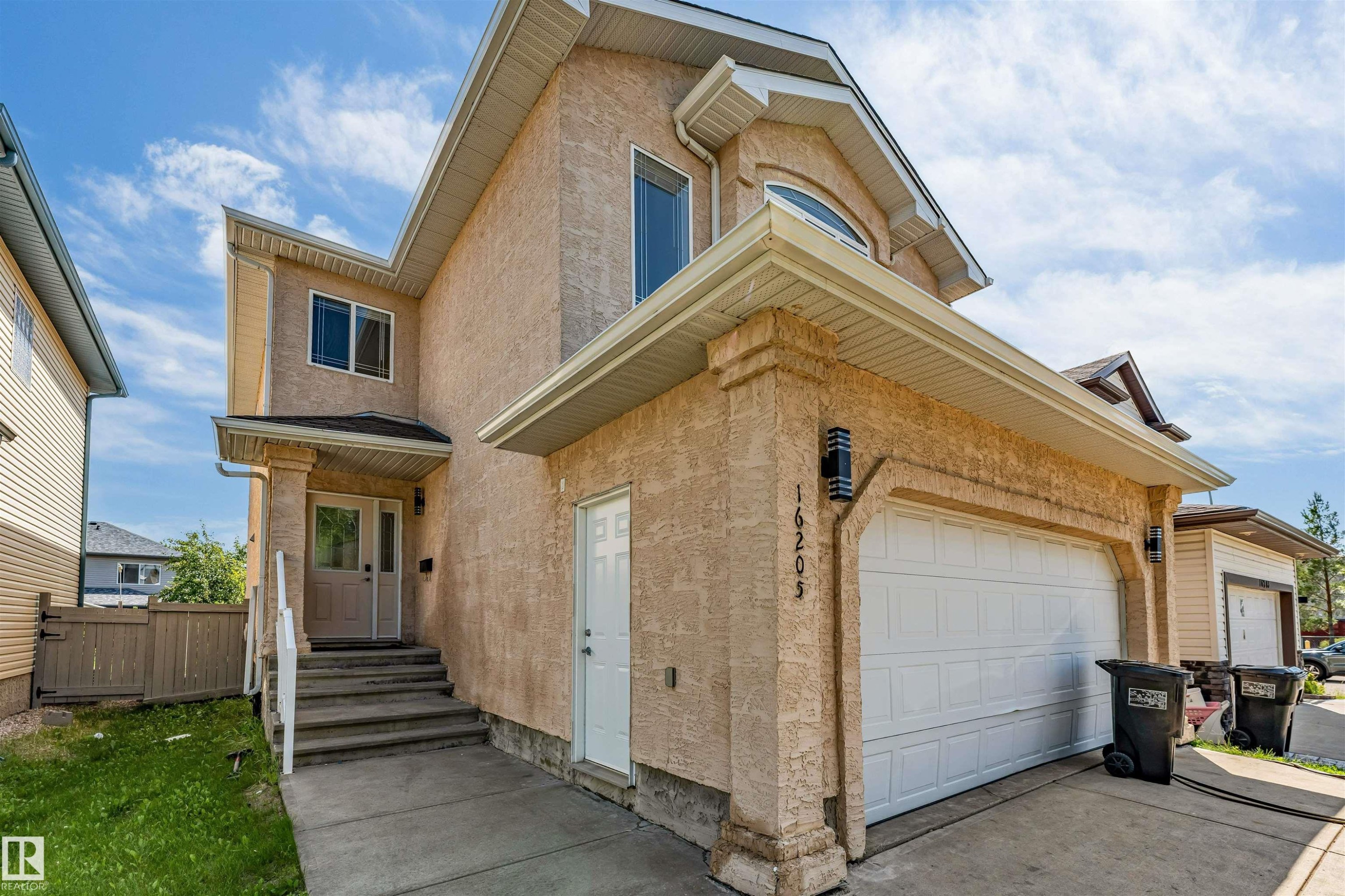 Stucco exterior with an integrated two-car garage featuring a white panel door - 16205 55 Street Nw, Edmonton, AB - Outdoor