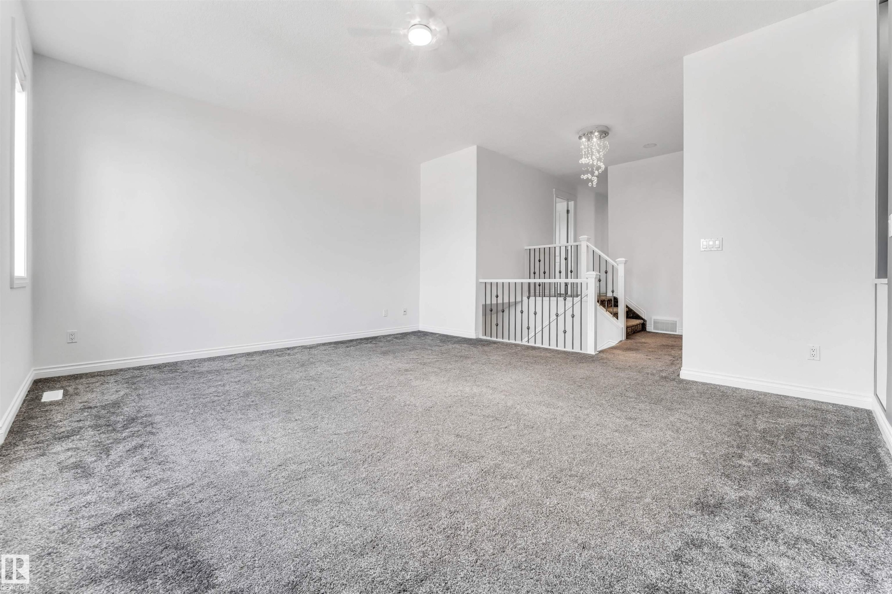 Spacious interior room featuring plush gray carpeting, white painted walls, and a ceiling fan with integrated lighting - 16205 55 Street Nw, Edmonton, AB - Indoor Photo Showing Other Room
