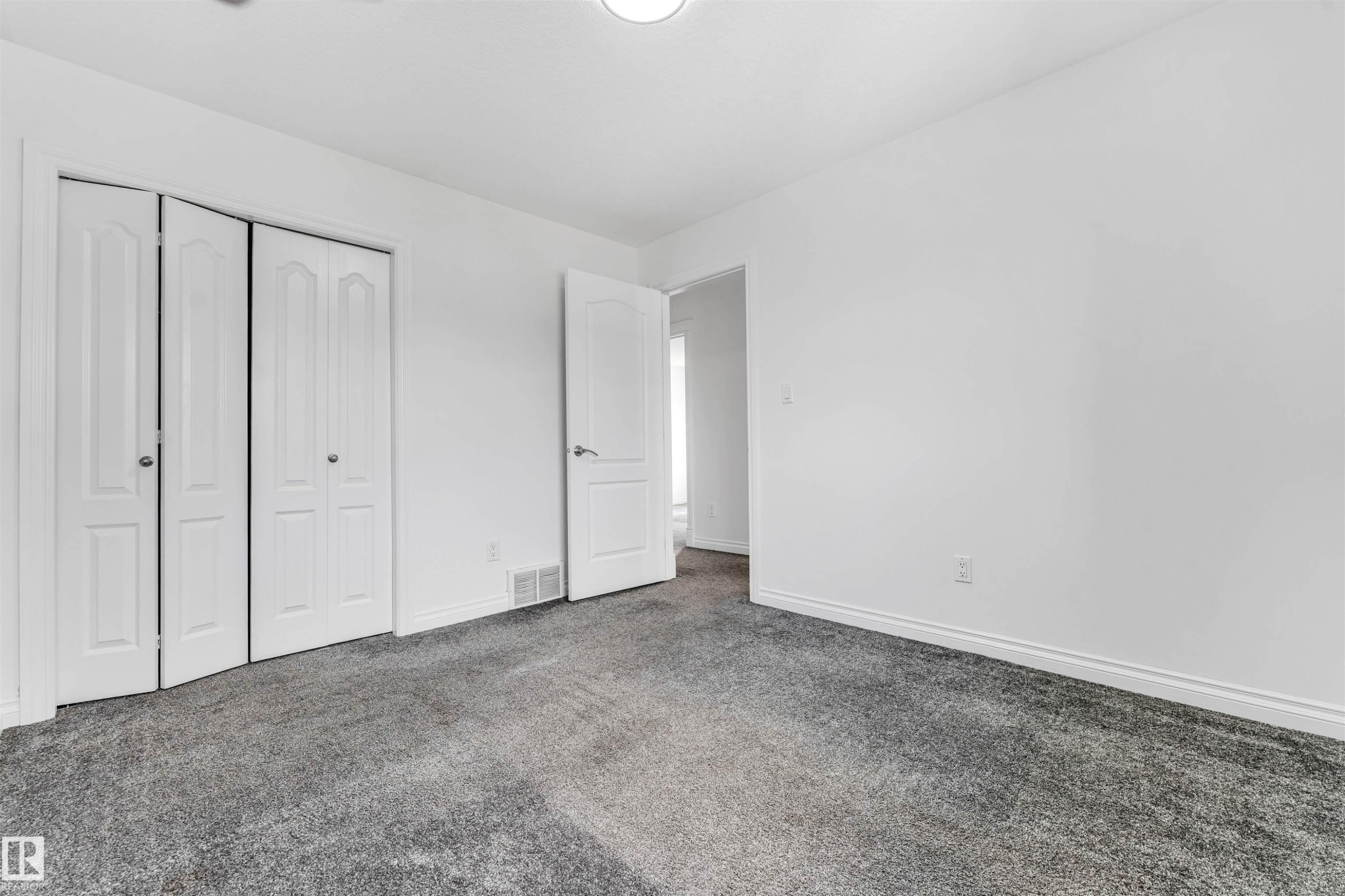Spacious room featuring neutral grey carpet flooring and white painted walls - 16205 55 Street Nw, Edmonton, AB - Indoor Photo Showing Other Room