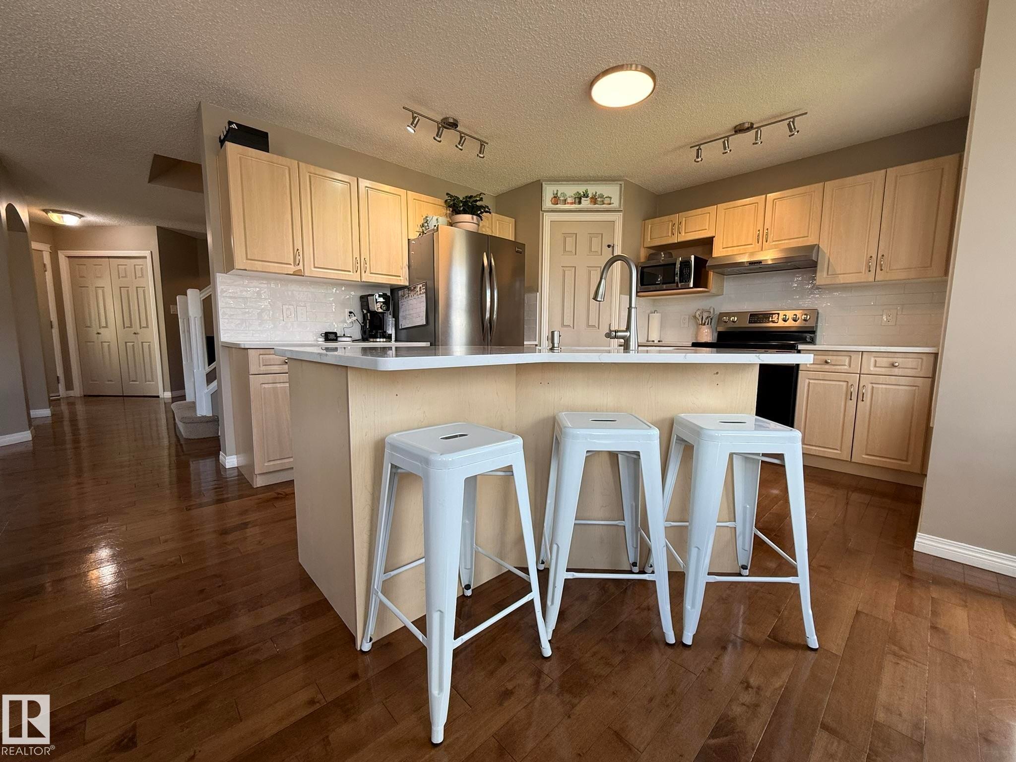 Kitchen with an island featuring a white countertop and seating for three - 1820 Robertson Crescent Sw, Edmonton, AB - Indoor Photo Showing Kitchen