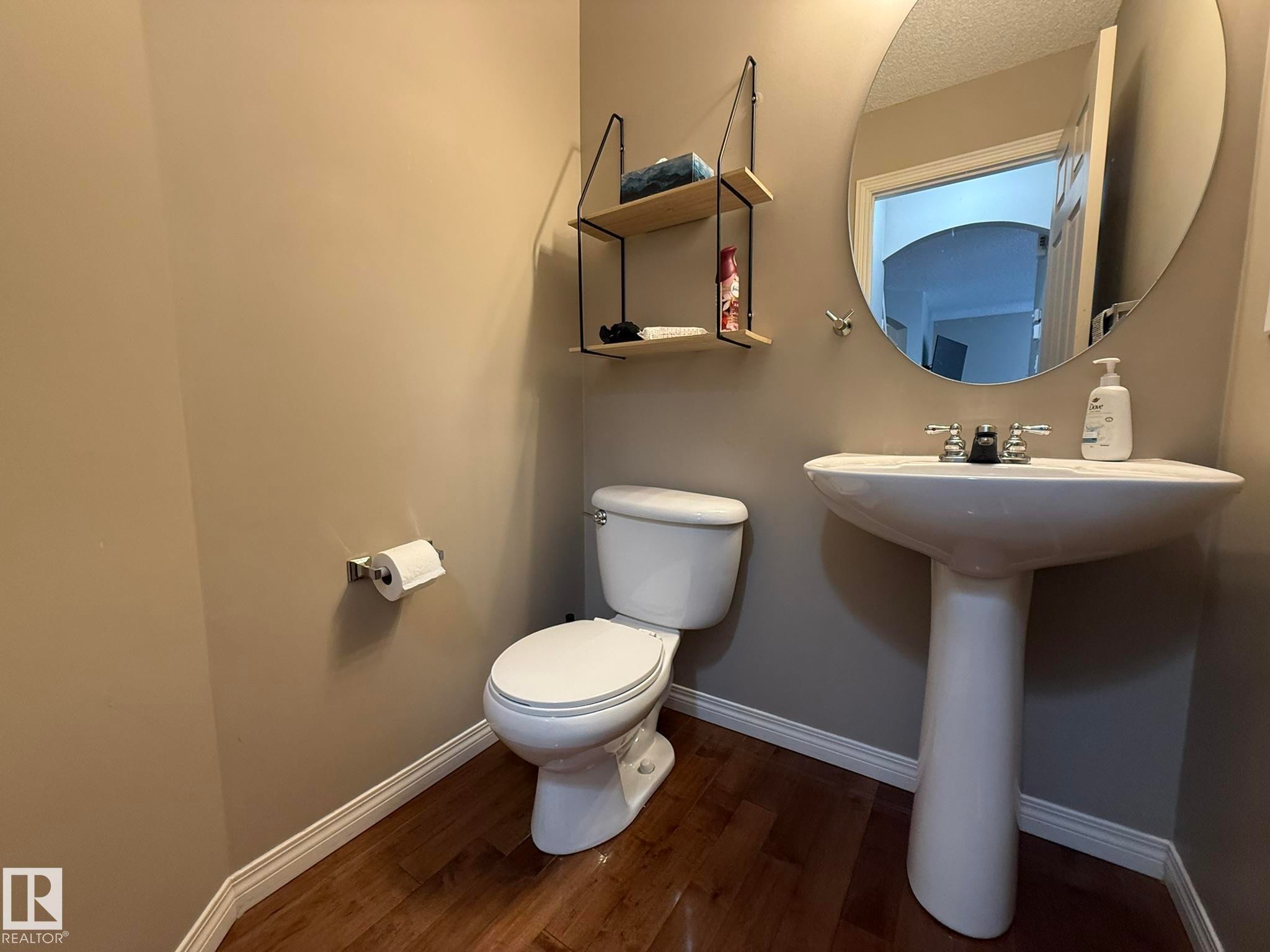 Pedestal sink with chrome fixtures and a circular mirror - 1820 Robertson Crescent Sw, Edmonton, AB - Indoor Photo Showing Bathroom