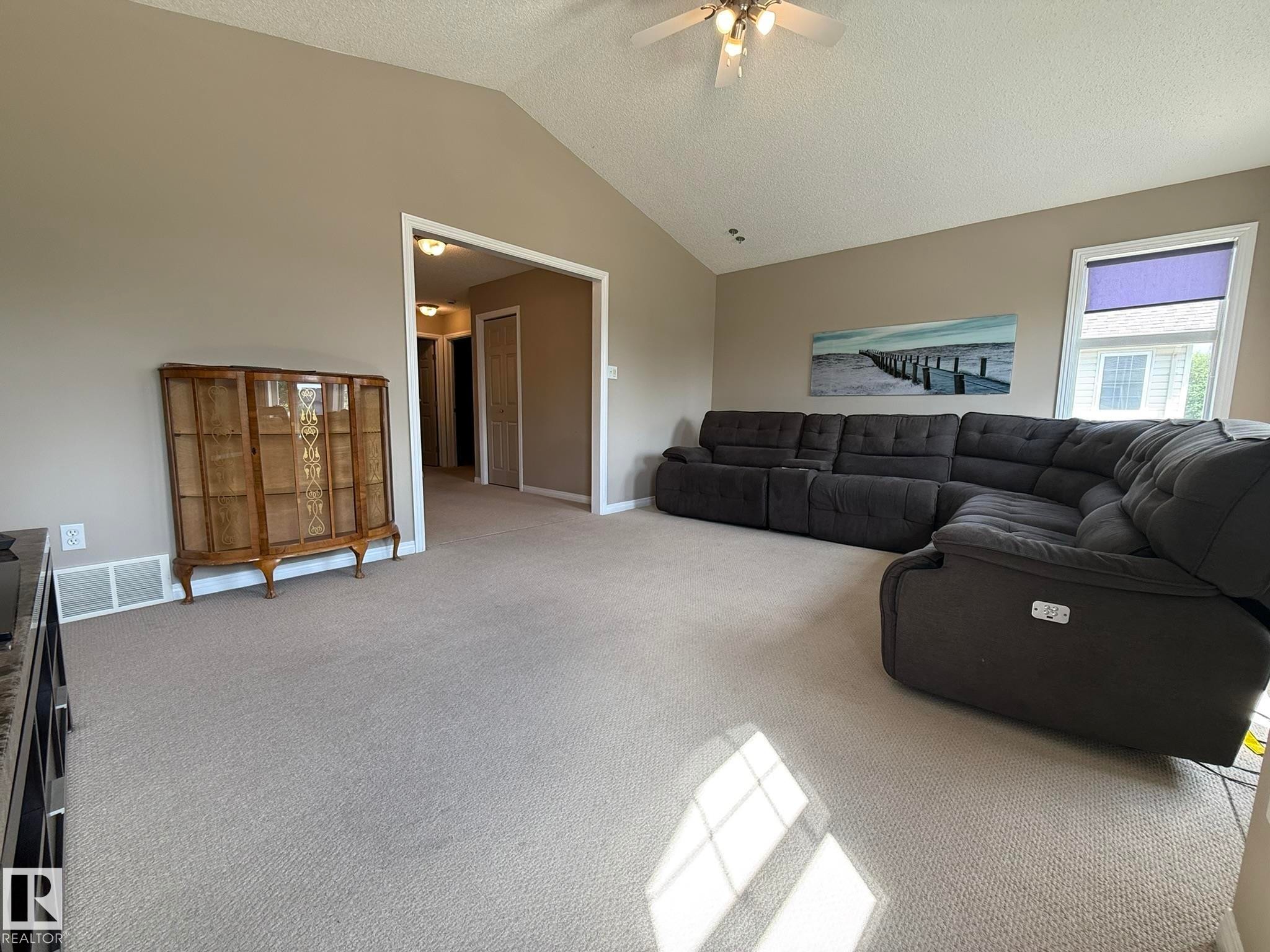 Vaulted ceiling living area featuring neutral carpeting and light tan wall paint - 1820 Robertson Crescent Sw, Edmonton, AB - Indoor