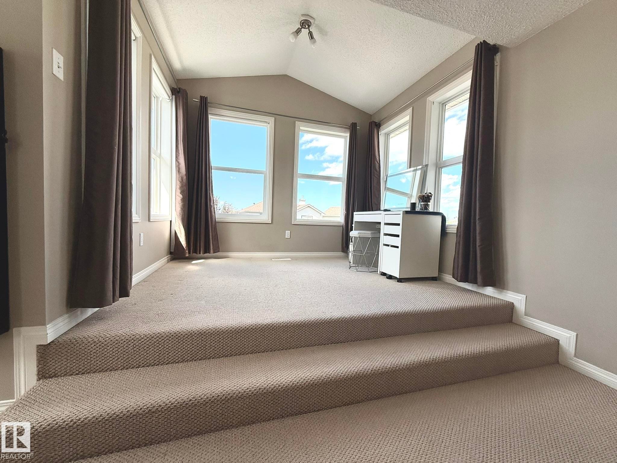 Carpeted loft space featuring a vaulted ceiling and multiple windows - 1820 Robertson Crescent Sw, Edmonton, AB - Indoor Photo Showing Other Room