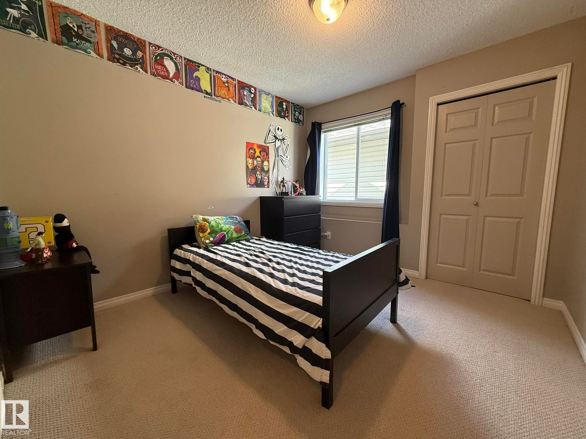 Carpeted bedroom featuring a neutral wall color, white trim, a double window with blinds, and a bi-fold closet door - 1820 Robertson Crescent Sw, Edmonton, AB - Indoor Photo Showing Bedroom