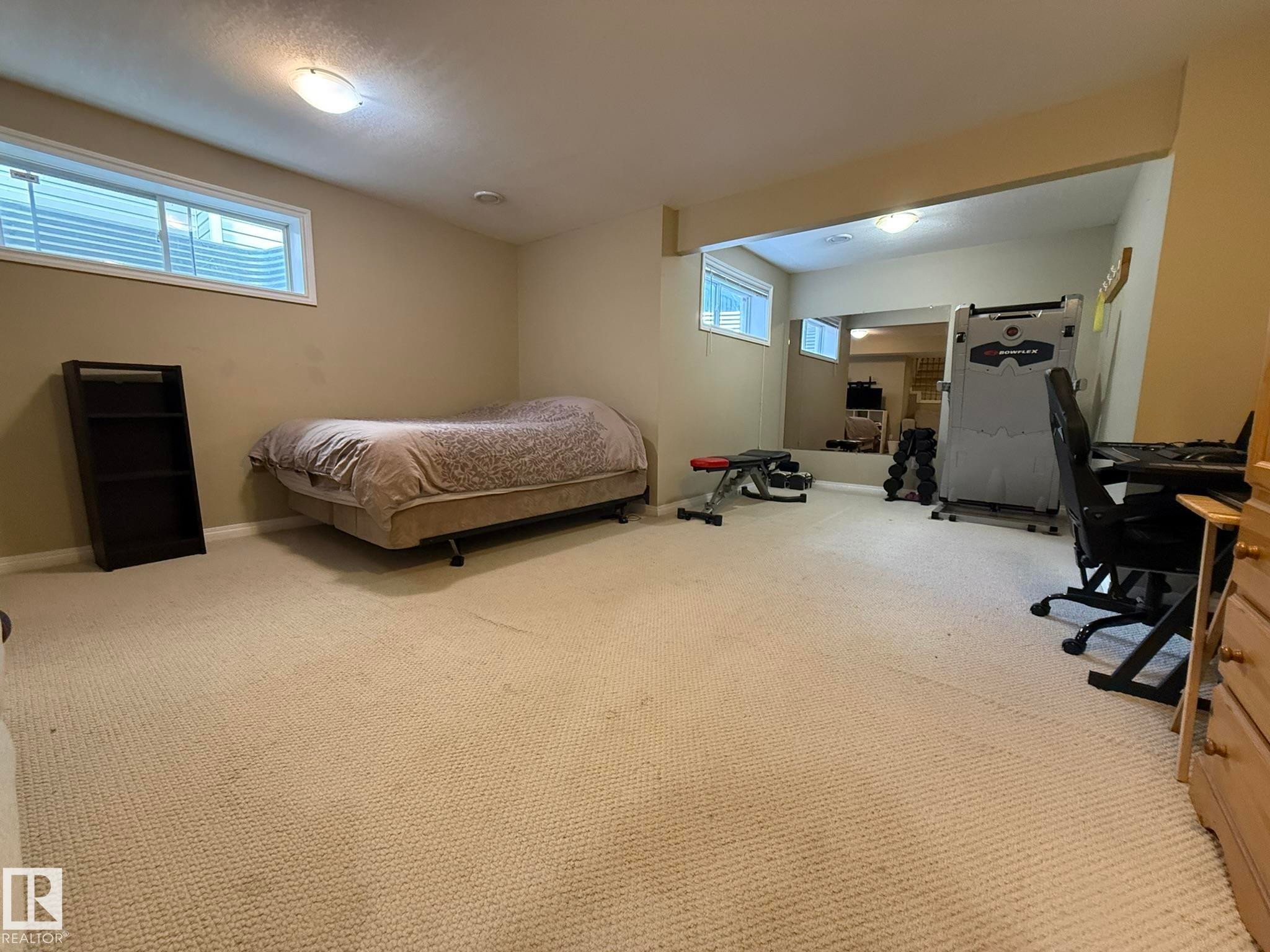 Carpeted room featuring light beige walls, a built-in recessed ceiling light, and a window with a white frame - 1820 Robertson Crescent Sw, Edmonton, AB - Indoor