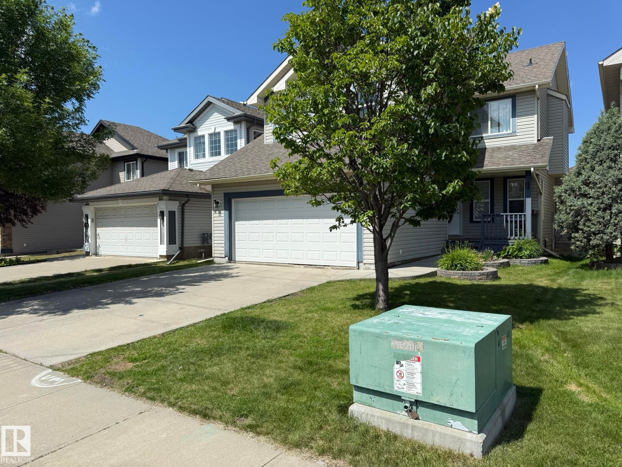 Two-story residence featuring light-colored siding, a covered front entry, and a two-car attached garage - 1820 Robertson Crescent Sw, Edmonton, AB - Outdoor