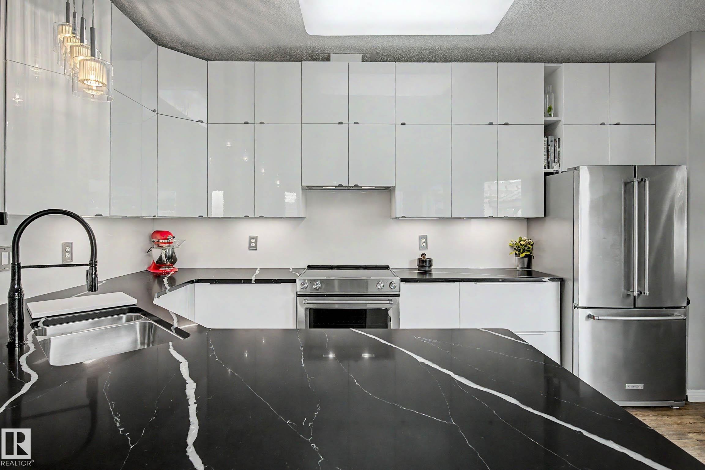 Kitchen featuring black stone countertops with white veining, white high-gloss cabinetry, stainless steel appliances, and a black gooseneck faucet - 9130 100A Avenue Nw, Edmonton, AB - Indoor Photo Showing Kitchen With Upgraded Kitchen