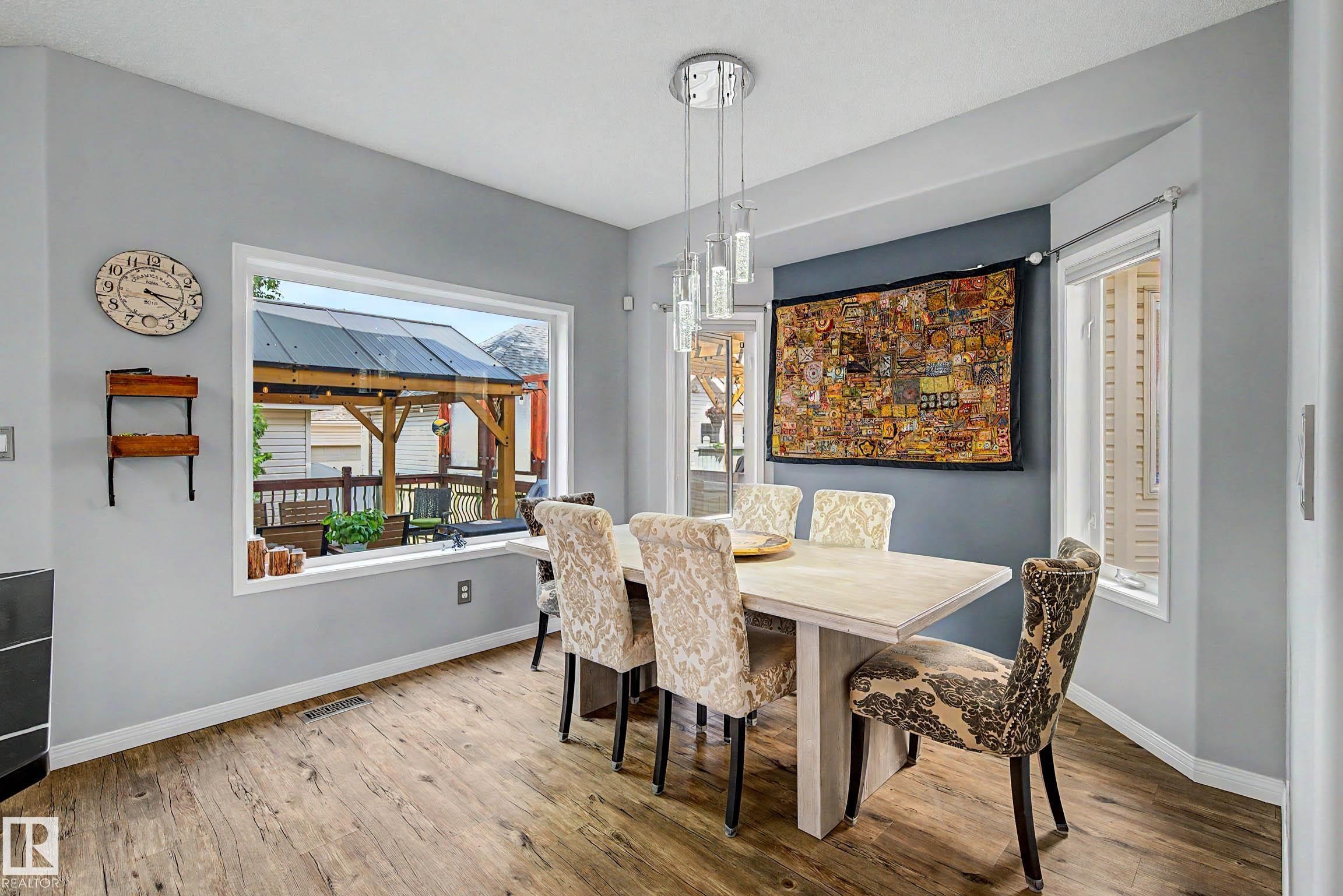 Dining area featuring wood-finish flooring and a large picture window - 9130 100A Avenue Nw, Edmonton, AB - Indoor Photo Showing Dining Room
